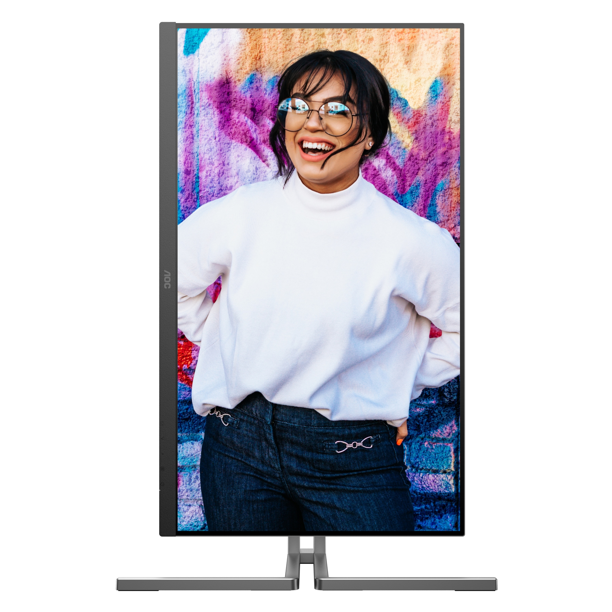 Monitor pokazuje uśmiechniętą kobietę w okularach na tle kolorowej ściany z graffiti.