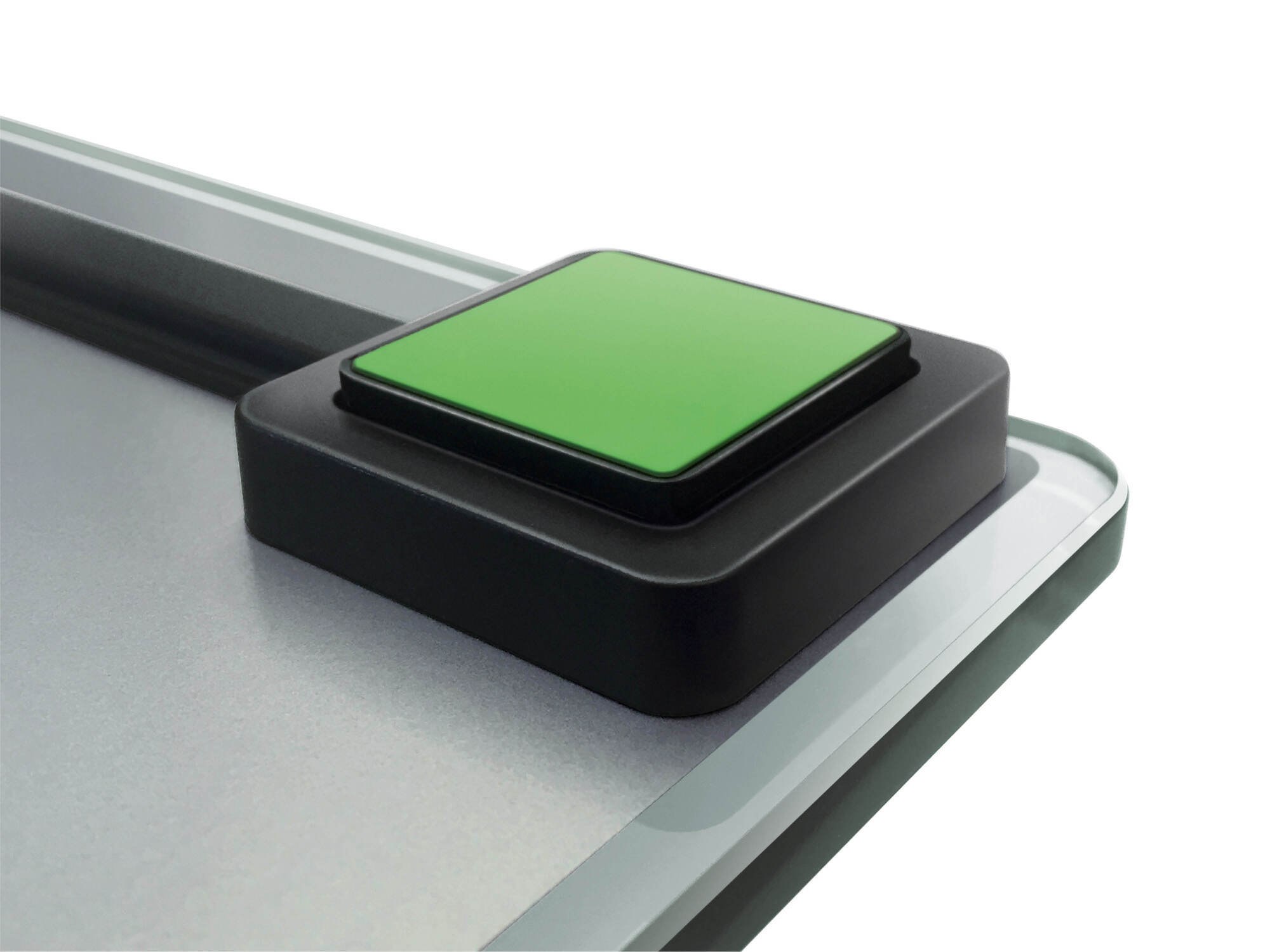 Zbliżenie wagi z zielonym przyciskiem. Waga jest srebrna i biała.