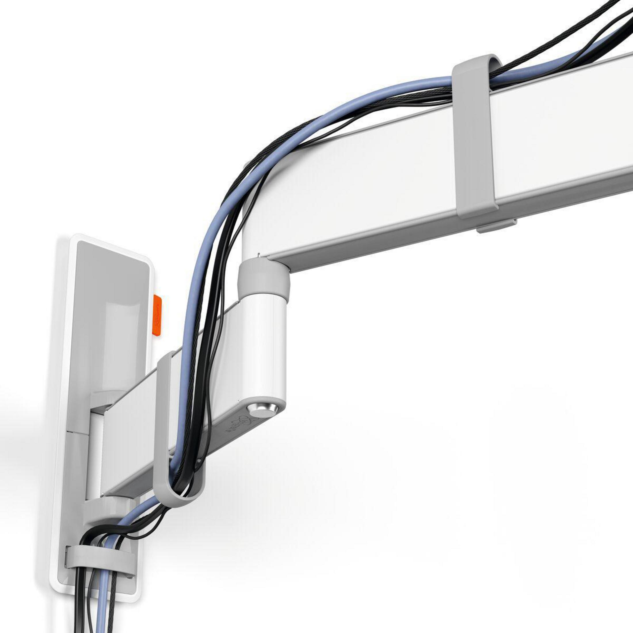 Biały system zarządzania kablami na białej ścianie, z kablami przechodzącymi przez niego.