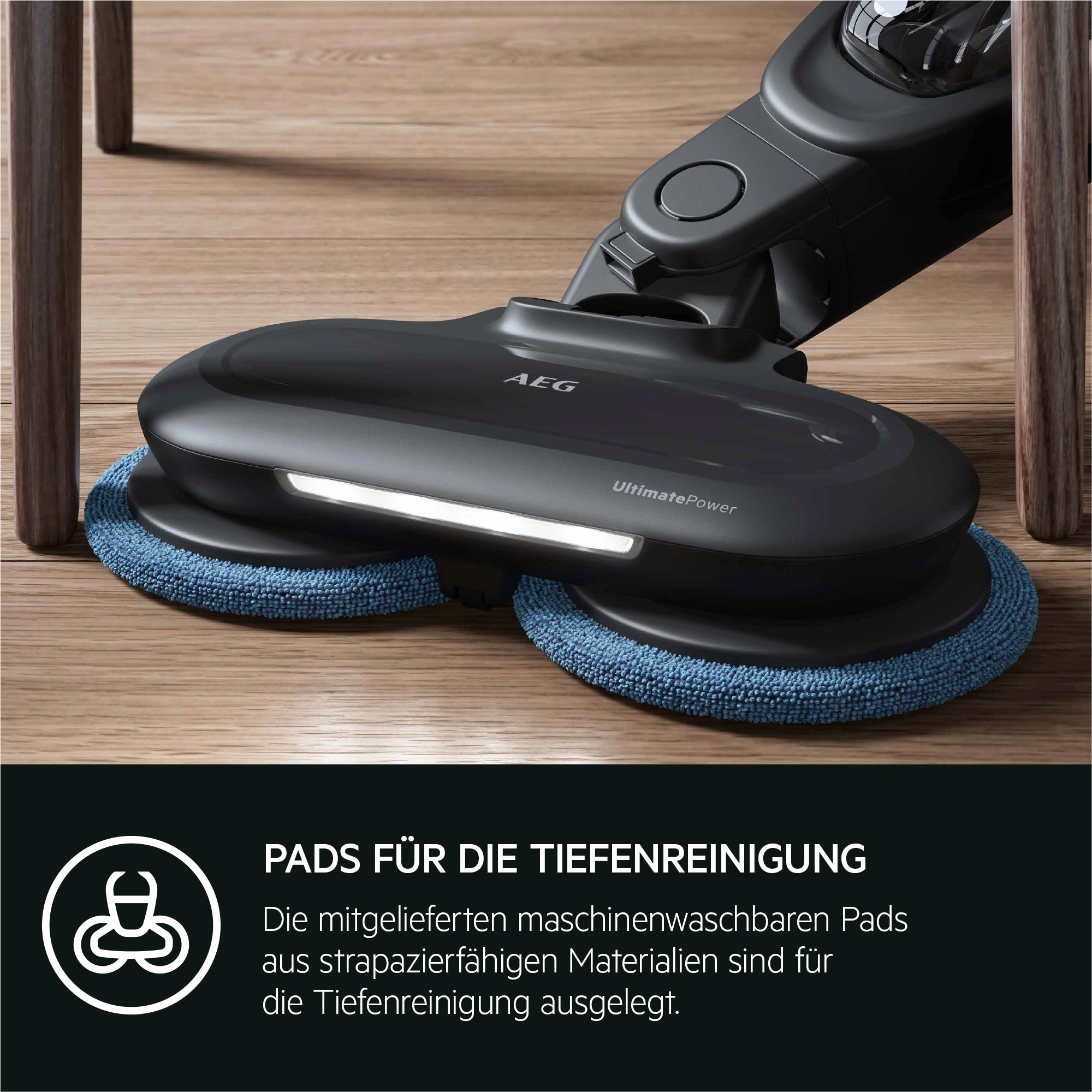 Cabezal de limpiador de suelo negro y azul oscuro con almohadillas azules. Fondo de suelo de madera y patas de muebles.