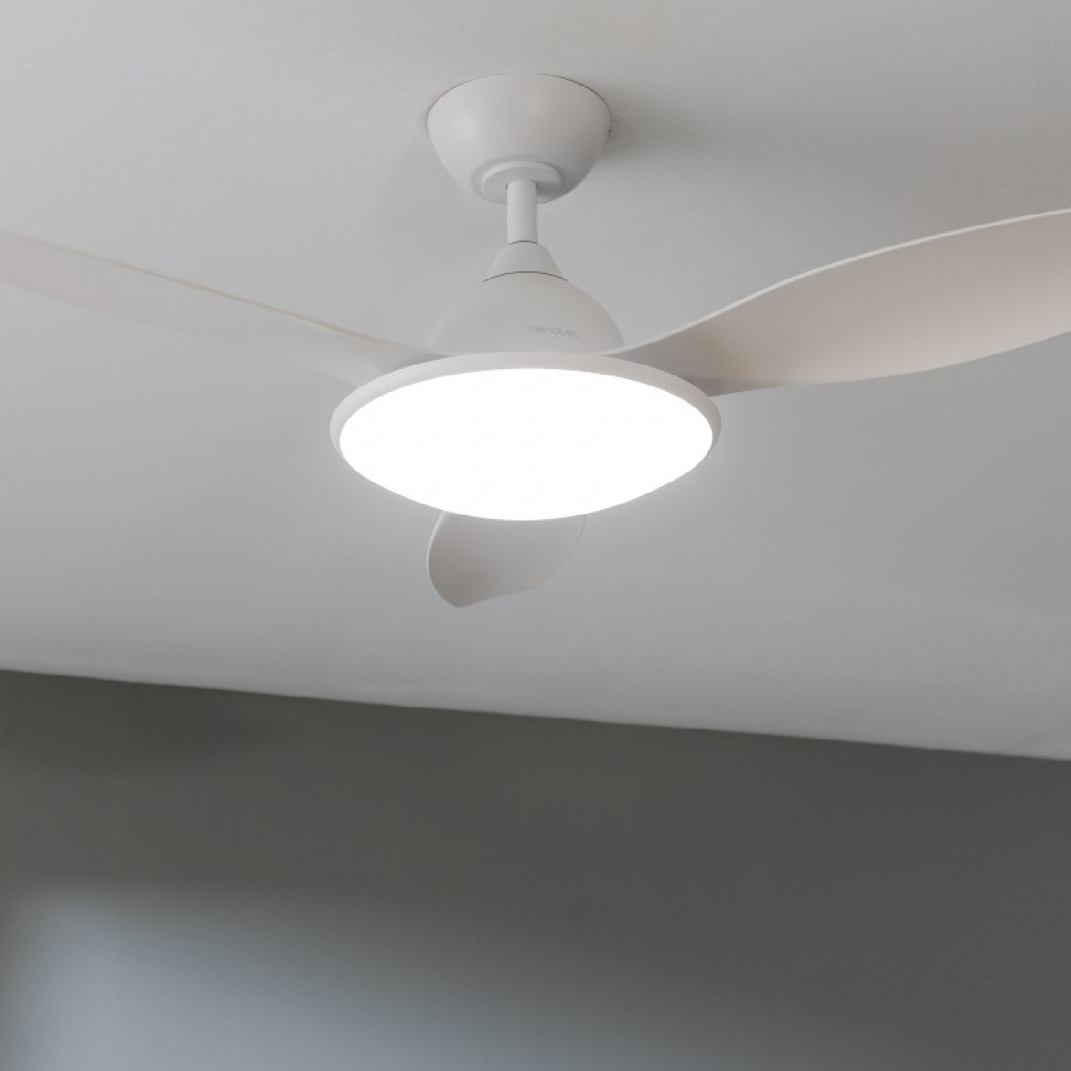 Un ventilatore da soffitto bianco con tre pale e una luce integrata, contro un soffitto bianco.
