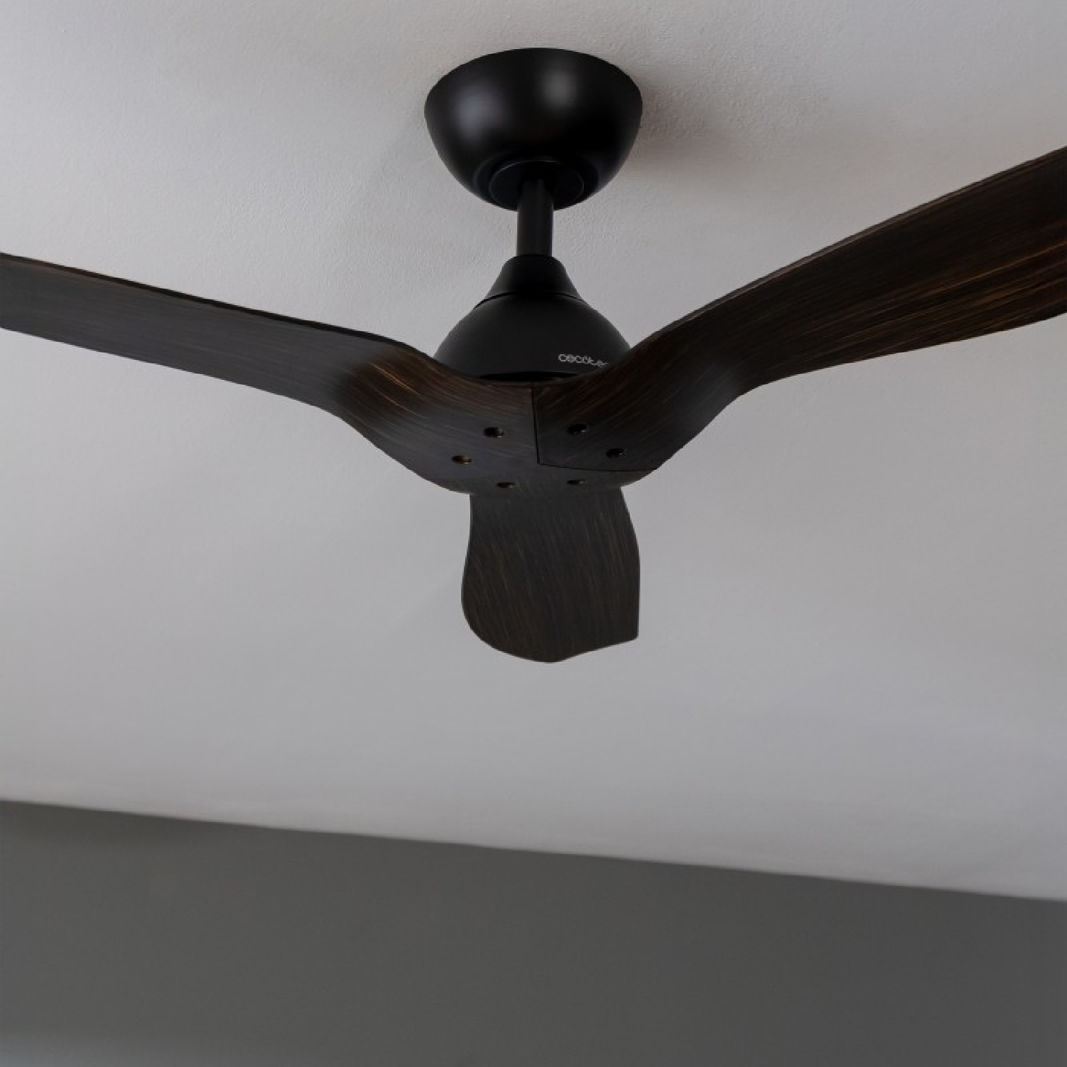 Ein schwarzer Deckenventilator mit drei Holzflügeln, montiert an einer weißen Decke.