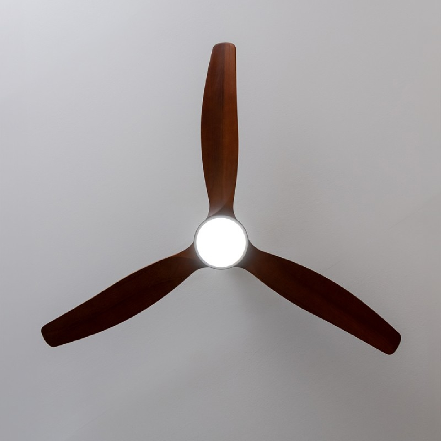 Ventilatore a soffitto a tre pale con luce centrale. Le pale sono in legno, montate su sfondo bianco.