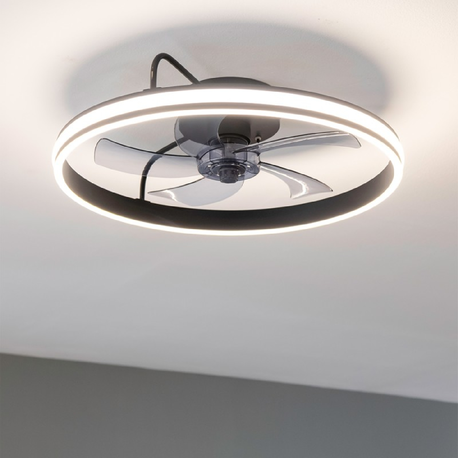 Deckenventilator mit kreisförmigem Licht und schwarzen und grauen Flügeln. Der Ventilator ist eingeschaltet.