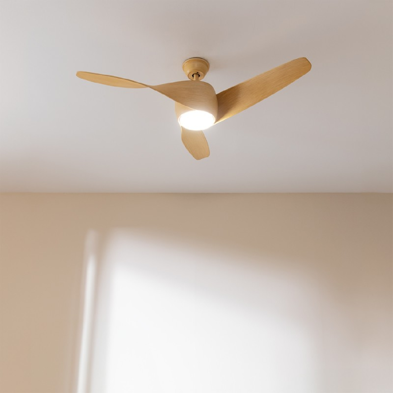 Un ventilatore da soffitto in legno con tre pale e una luce.
