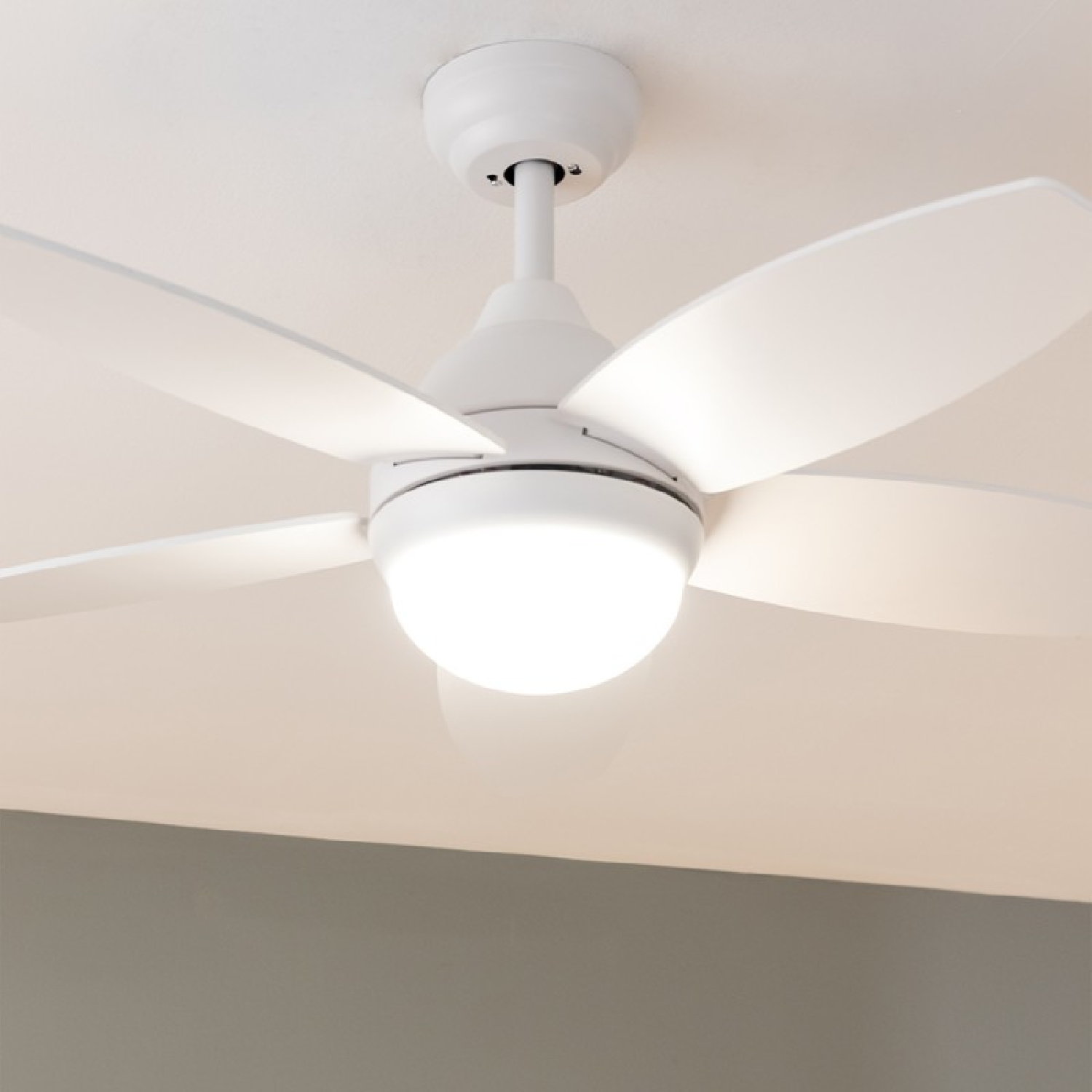 Ventilatore a soffitto bianco con quattro pale e luce centrale. Sfondo bianco.