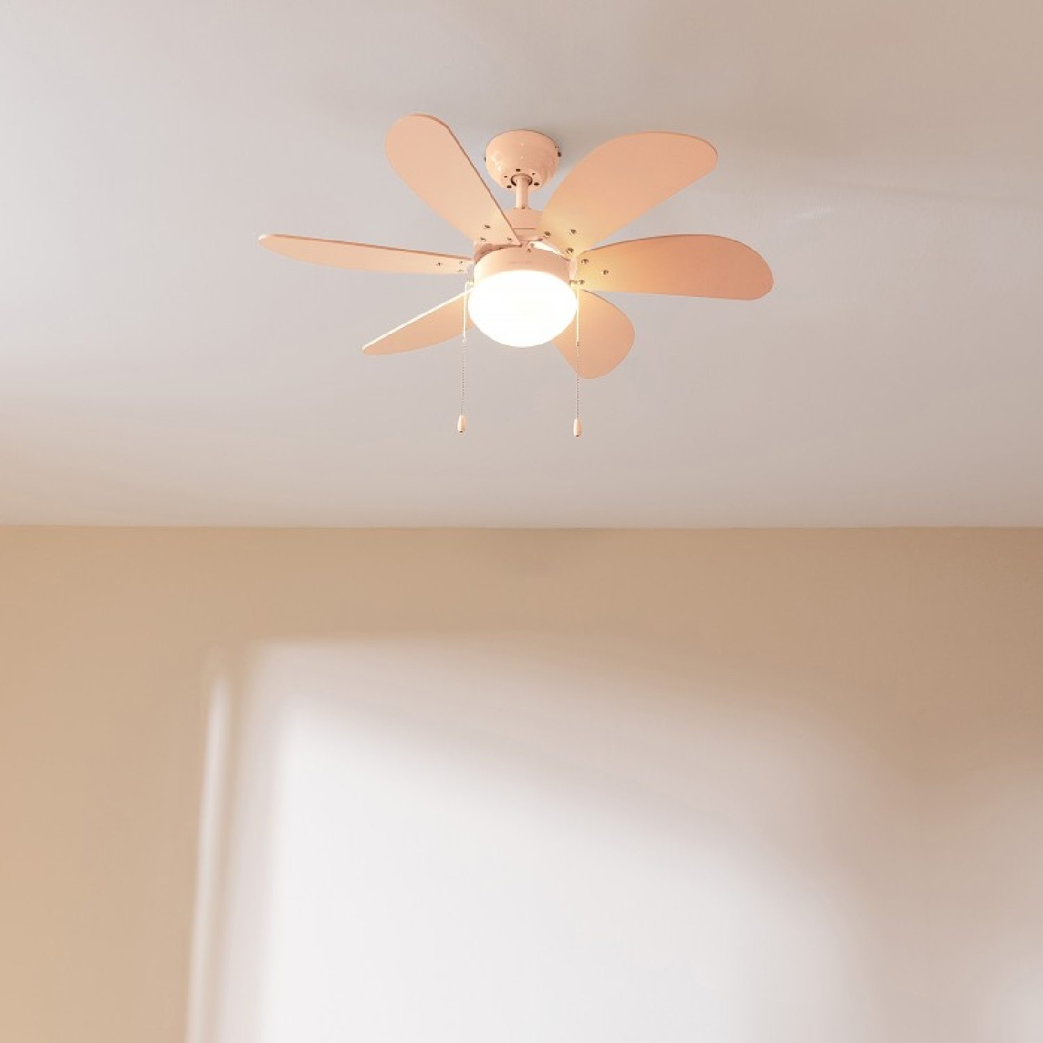 Un ventilador de techo rosa con seis aspas y una luz. El ventilador está montado en el techo blanco.