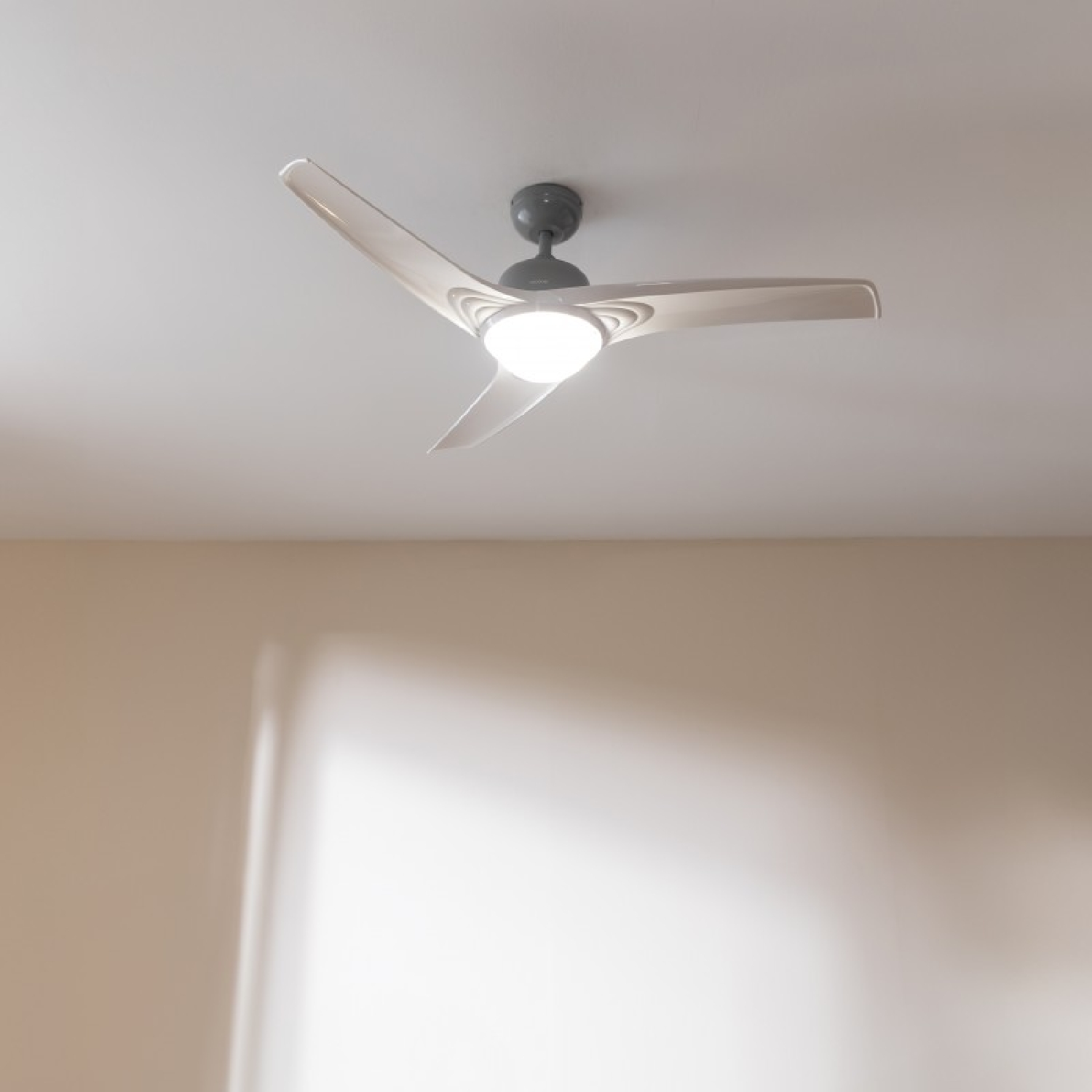 Un ventilatore da soffitto con tre pale e una luce. Il ventilatore è montato sul soffitto.