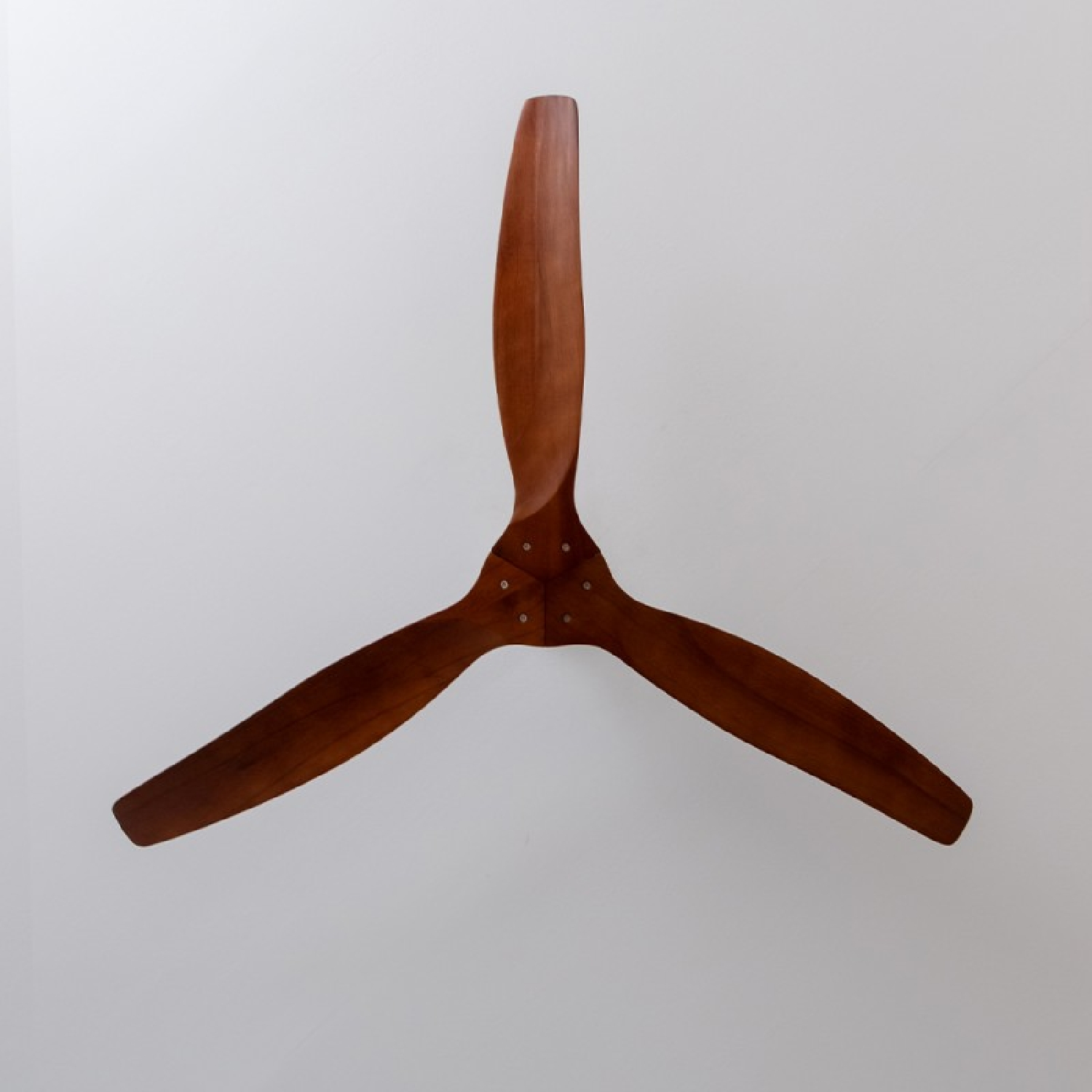 Ventilatore da soffitto con tre pale in legno montato su un soffitto bianco.