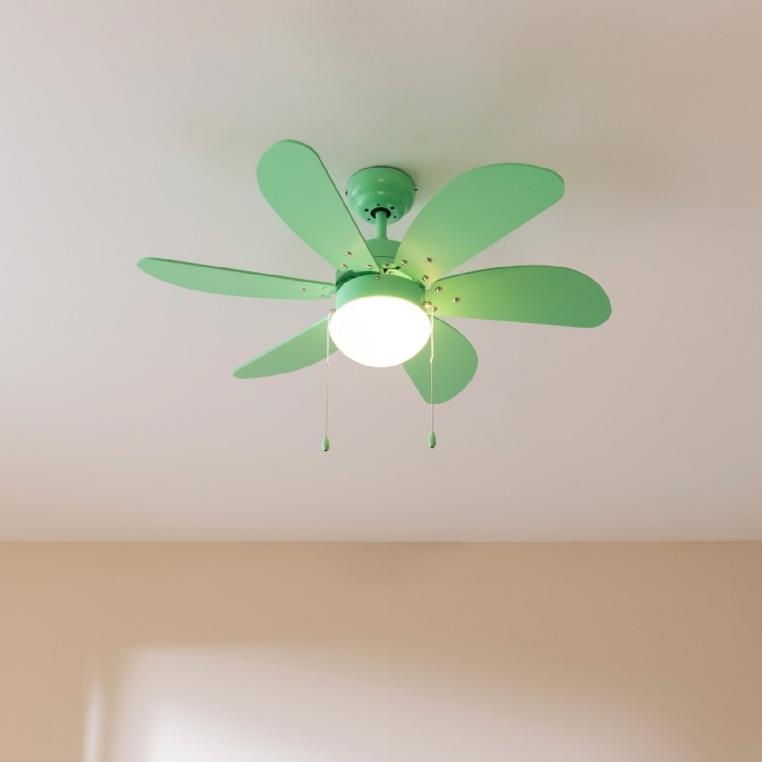 Ein Deckenventilator mit sechs grünen Flügeln und einem Licht in der Mitte. Die Flügel sind grün und das Licht ist an.
