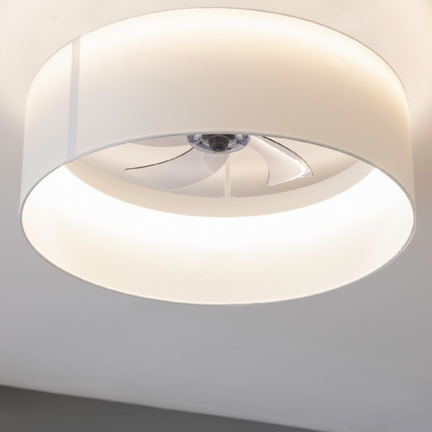 Luce da soffitto rotonda con ventola all'interno. La luce è bianca, contro un soffitto bianco.