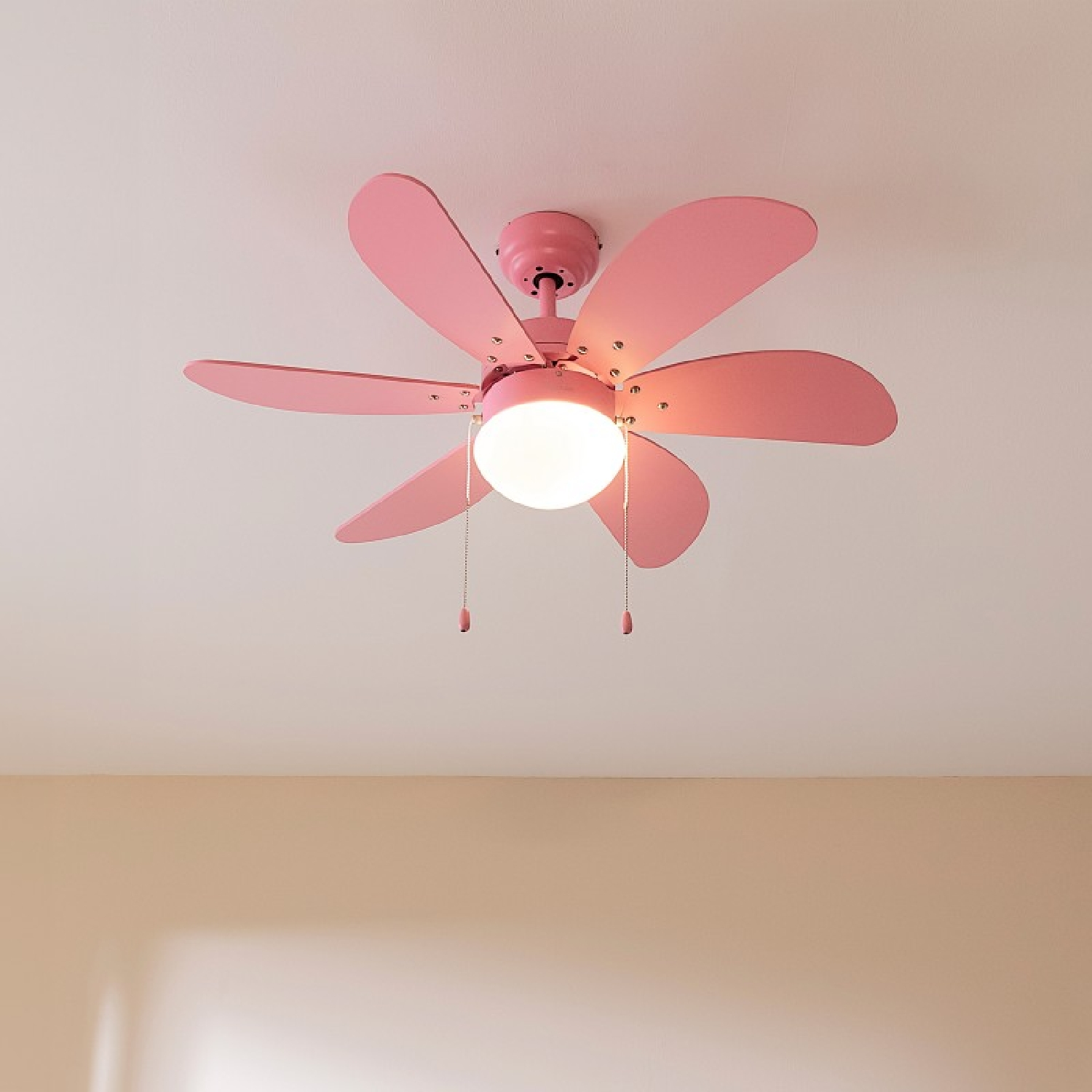 Un ventilatore da soffitto rosa con sei pale e una luce centrale, visto dal basso.