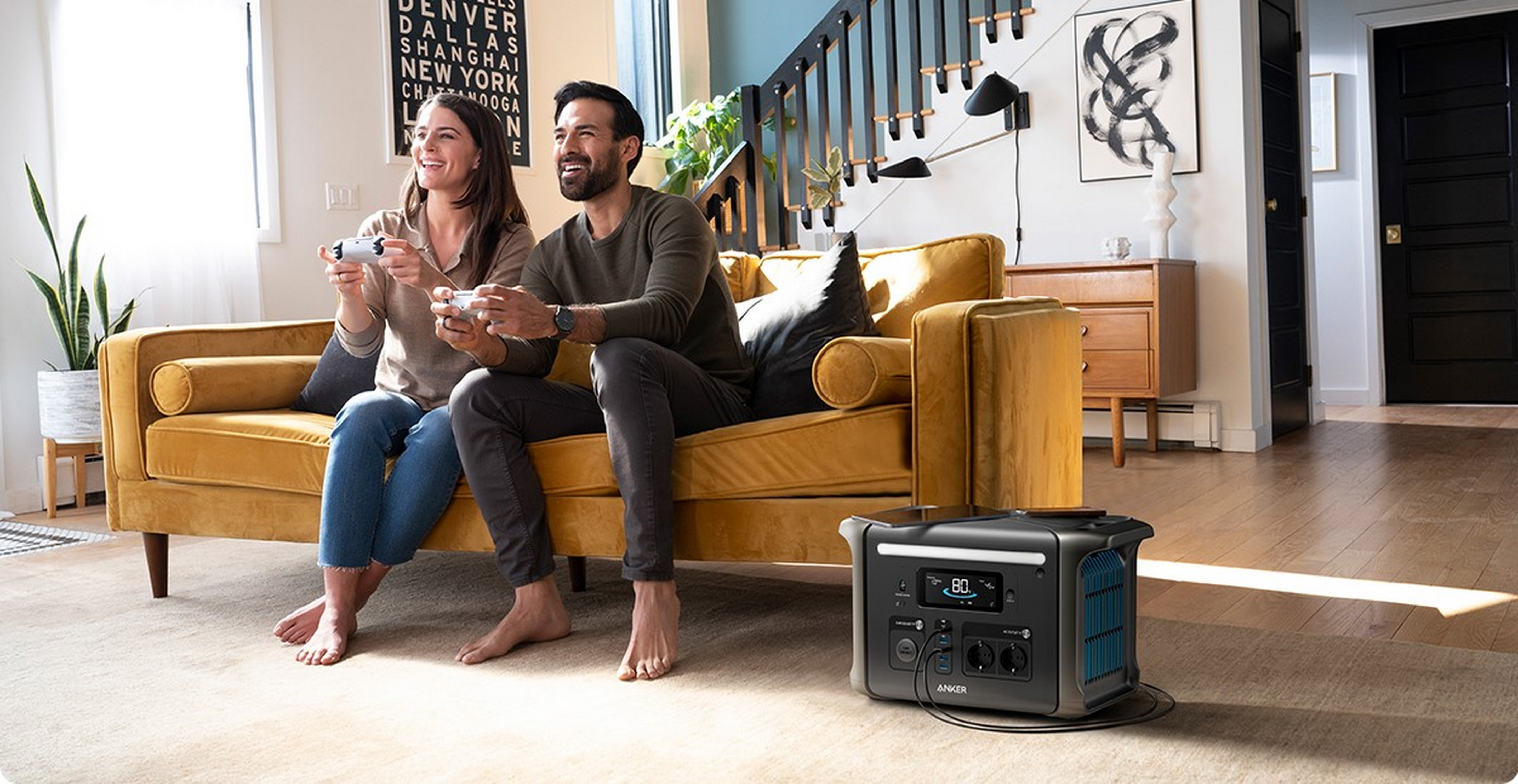 Para siedzi na żółtej kanapie grając w gry wideo, z elektrownią na podłodze.