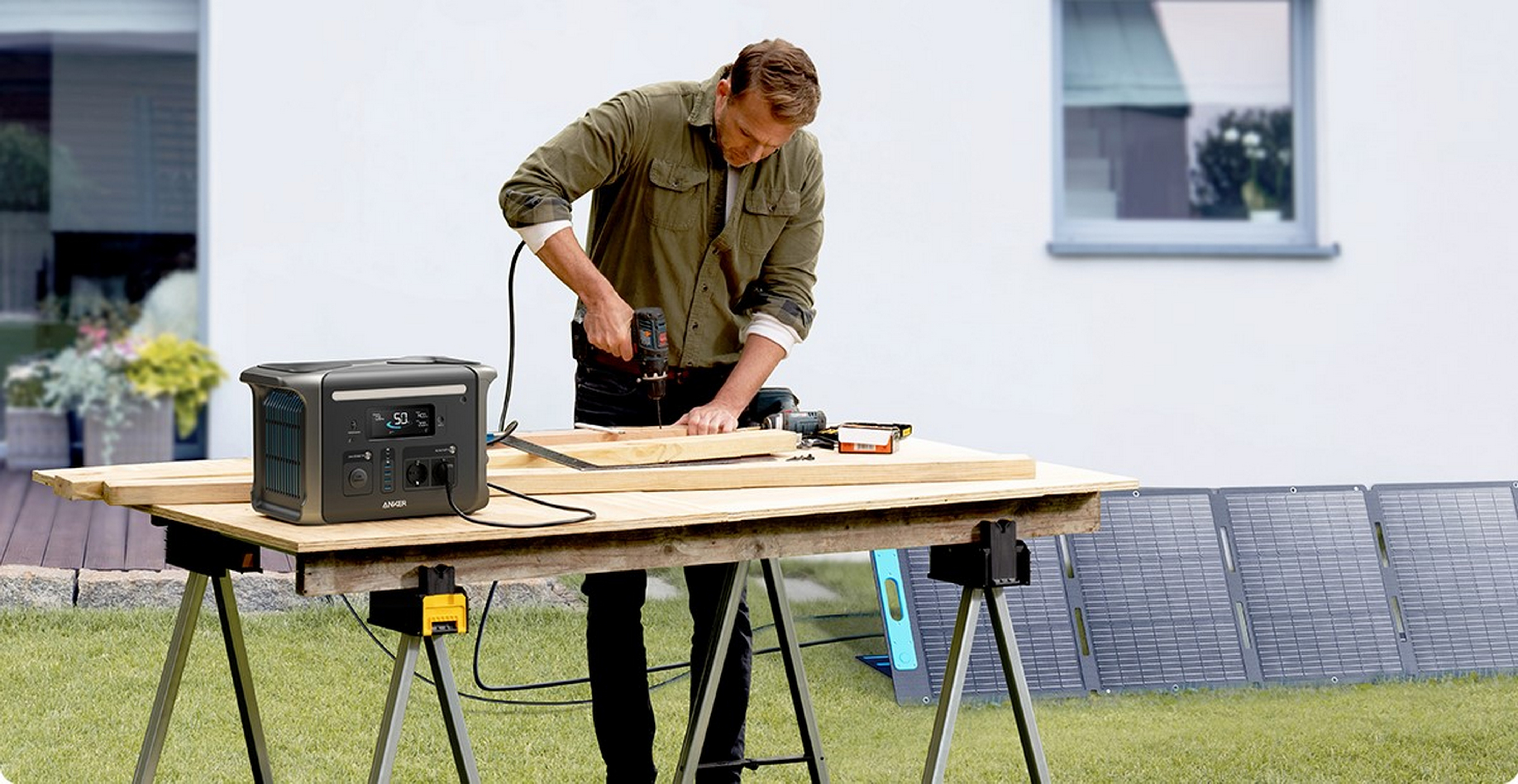 Mężczyzna używający wiertarki do drewna na zewnątrz, z elektrownią i panelami słonecznymi.