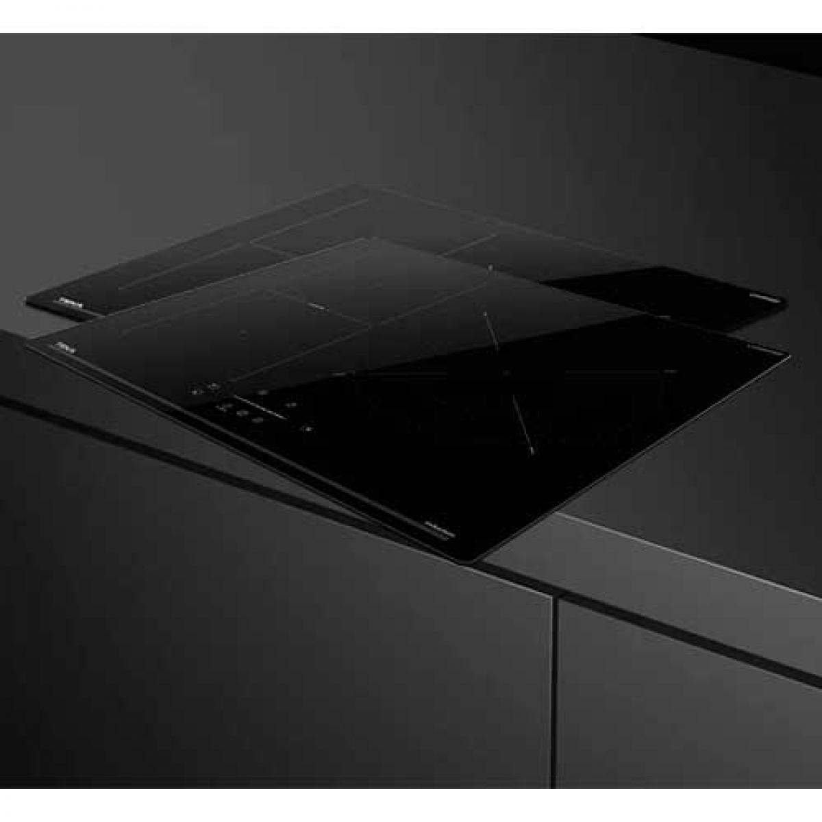 Dwie czarne, eleganckie płyty indukcyjne na ciemnej powierzchni. Płyty są lekko pochylone.