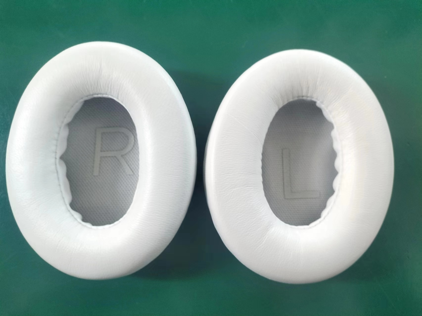 Dwie białe nauszniki z szarym wnętrzem.