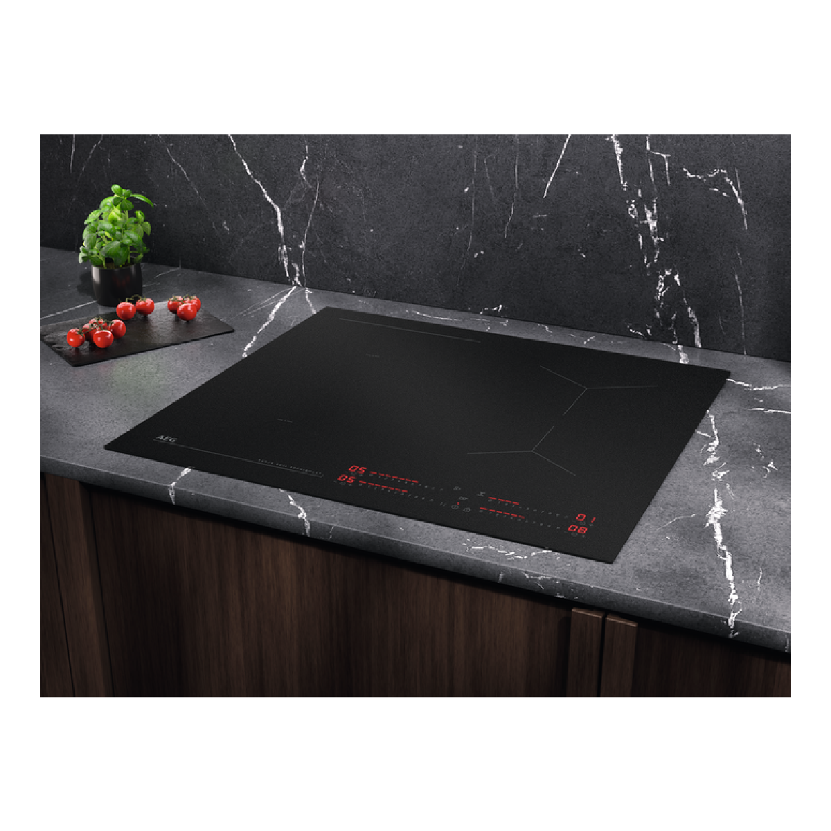 Piano cottura a induzione AEG nero. Display rosso e controlli touch. Piano di lavoro in marmo scuro con pomodori ed erbe.