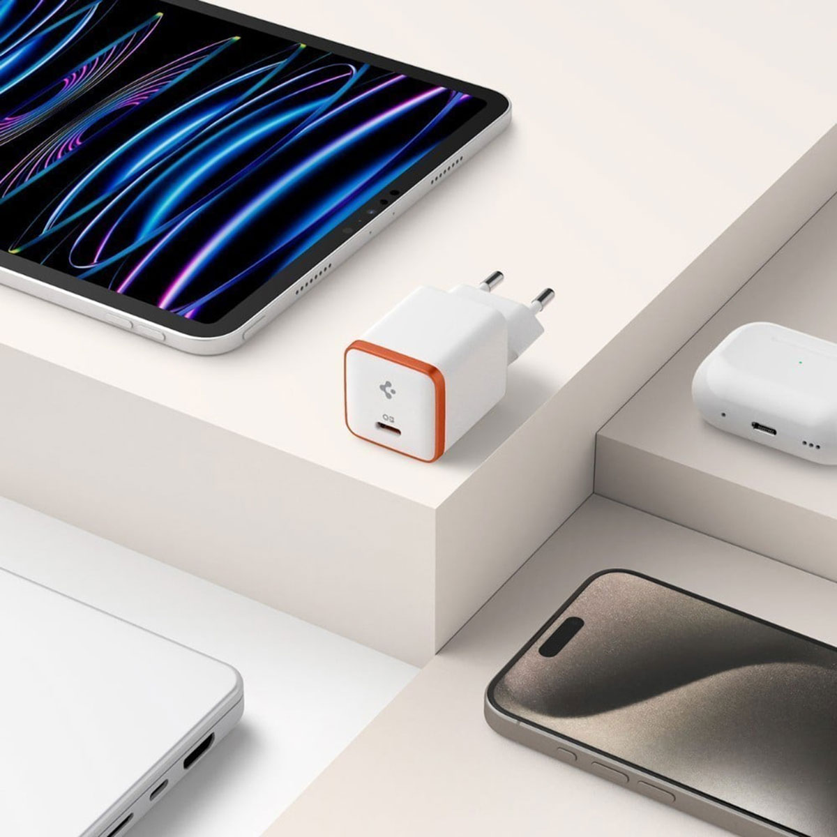 Witte en oranje oplader met apparaten waaronder een tablet en telefoon, op een wit oppervlak.