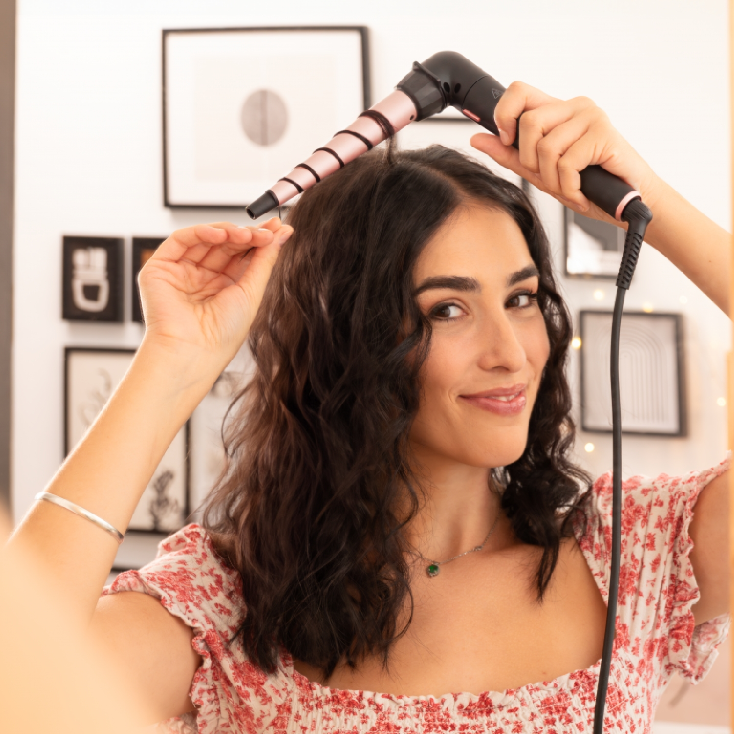 Donna che si arriccia i capelli con un arricciacapelli, specchio sullo sfondo.