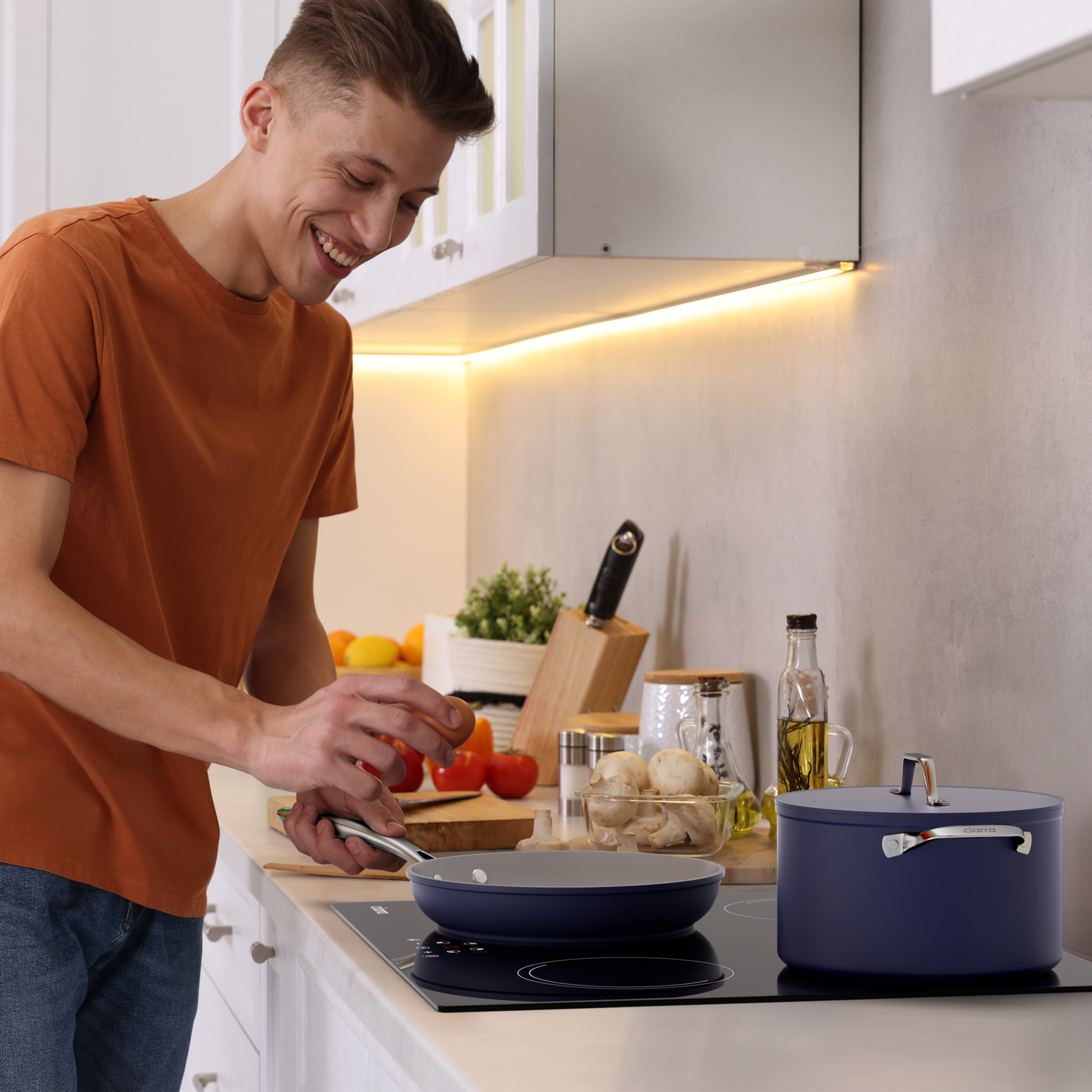Homme cuisinant dans une cuisine, poêle sur la cuisinière, casserole à côté.