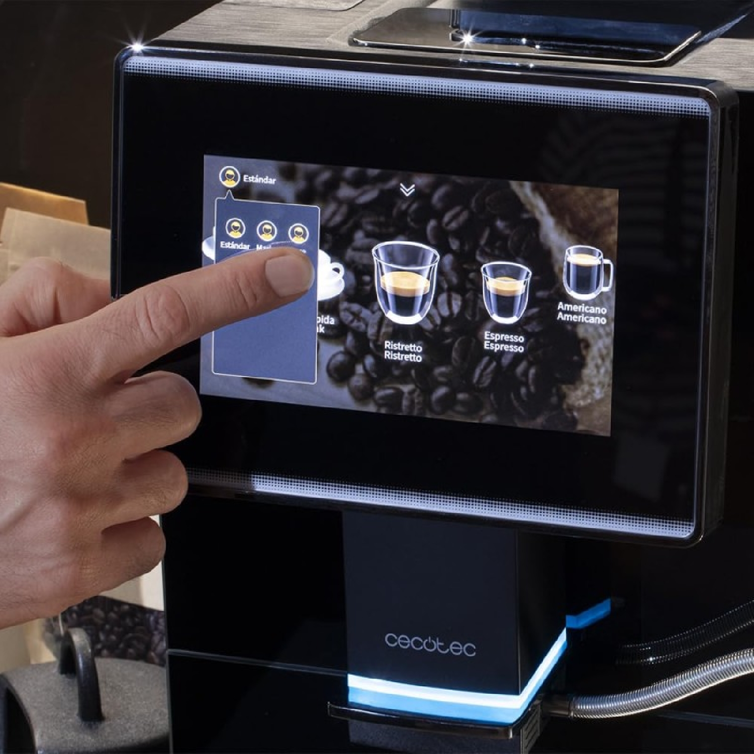 La mano de una persona toca la pantalla de una máquina de café, mostrando opciones de café.