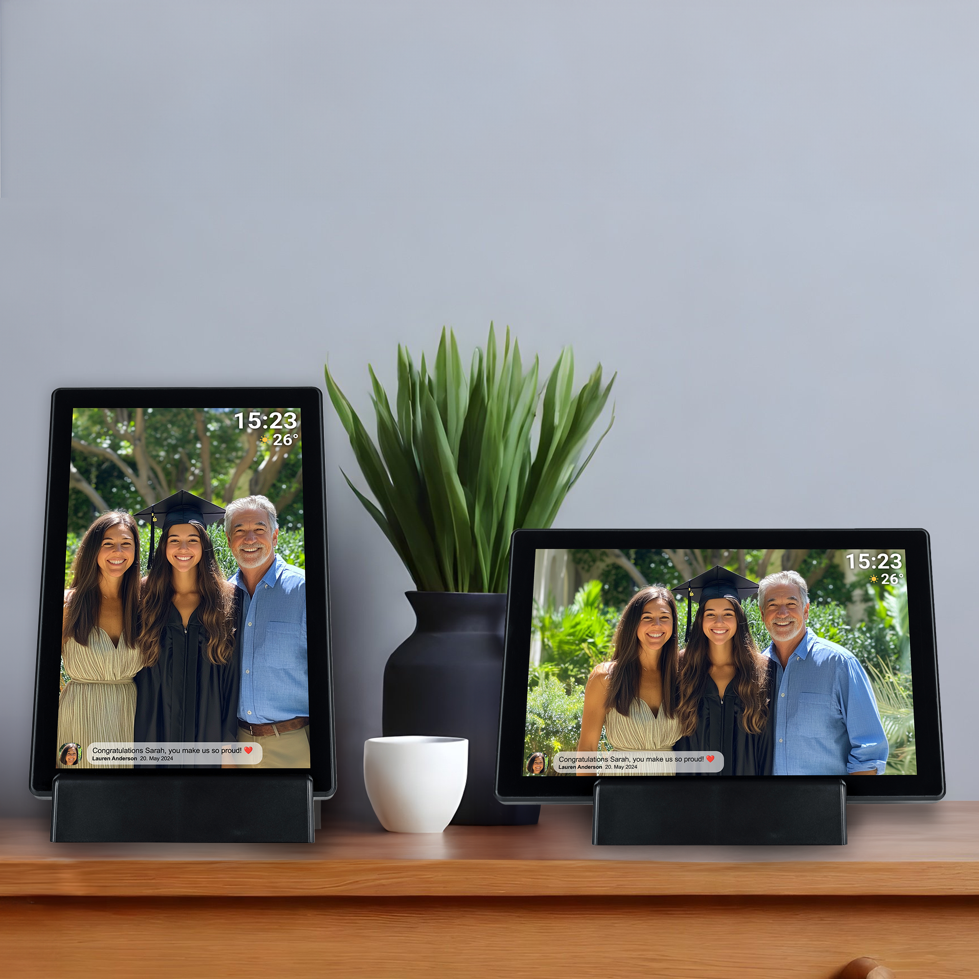 Two digital photo frames displaying photos of a family, with a vase and a plant.