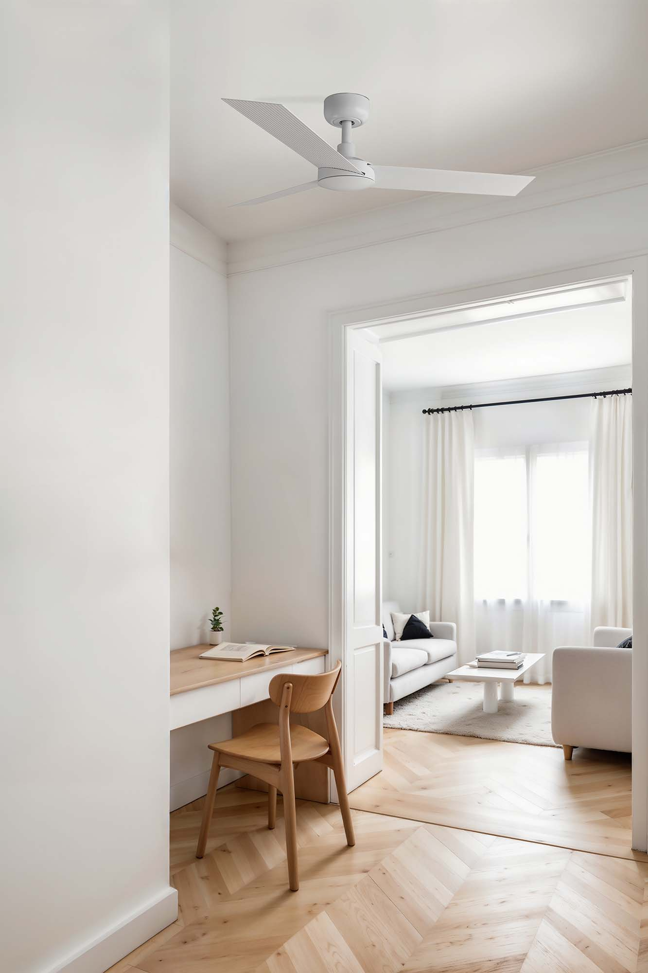 Heller, weißer Raum mit Schreibtisch, Stuhl und Deckenventilator.