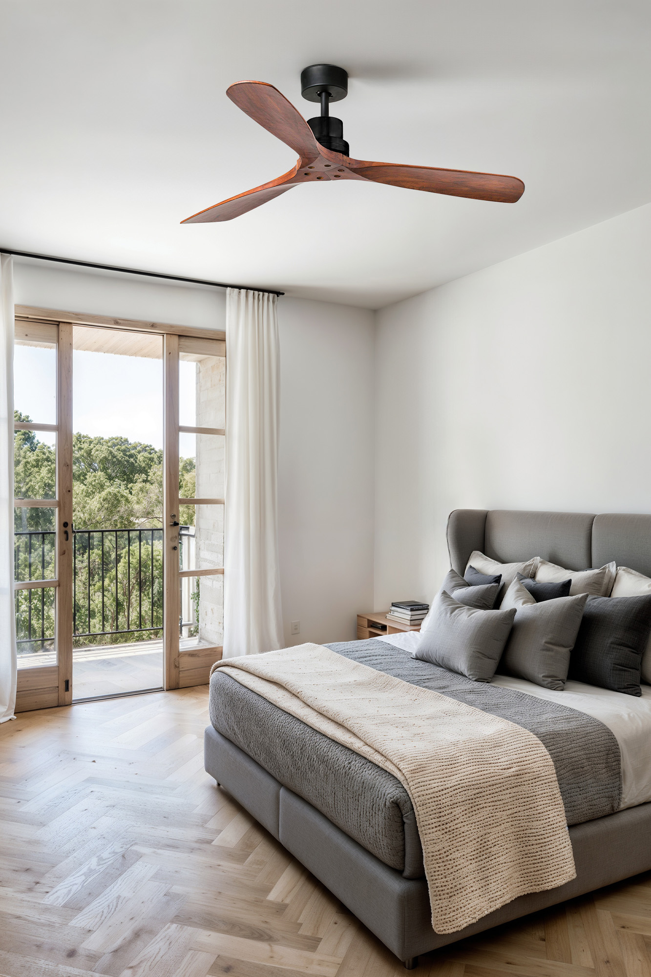 Camera da letto con ventilatore a soffitto, letto e vista balcone con alberi.