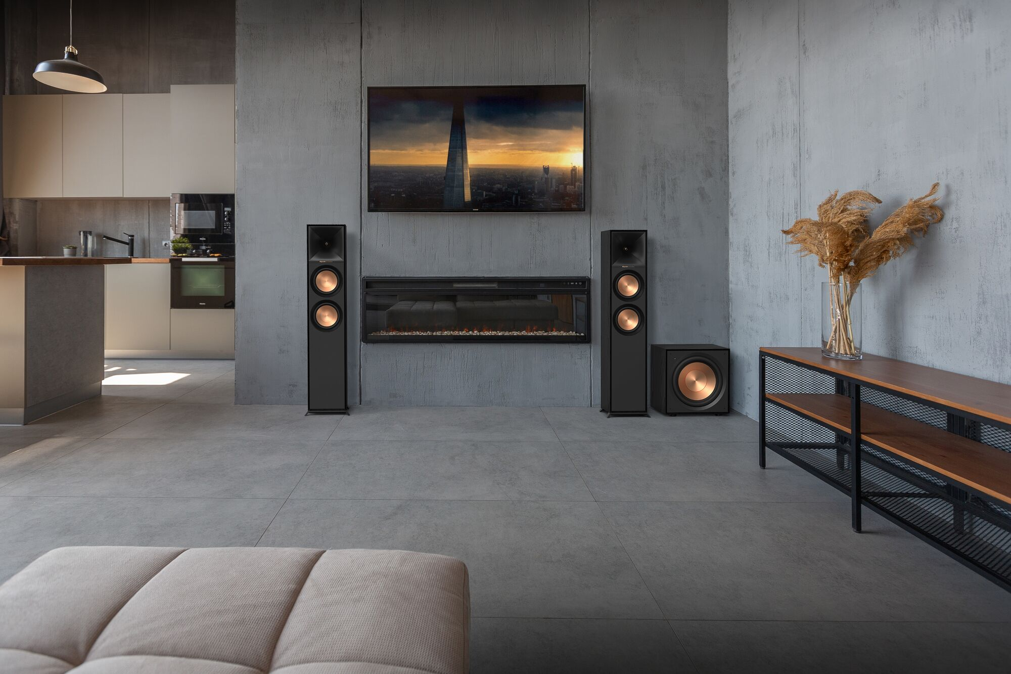 Ein modernes Wohnzimmer mit Fernseher, Lautsprechern und Kamin. Es gibt ein Sofa und ein Dekorationselement.