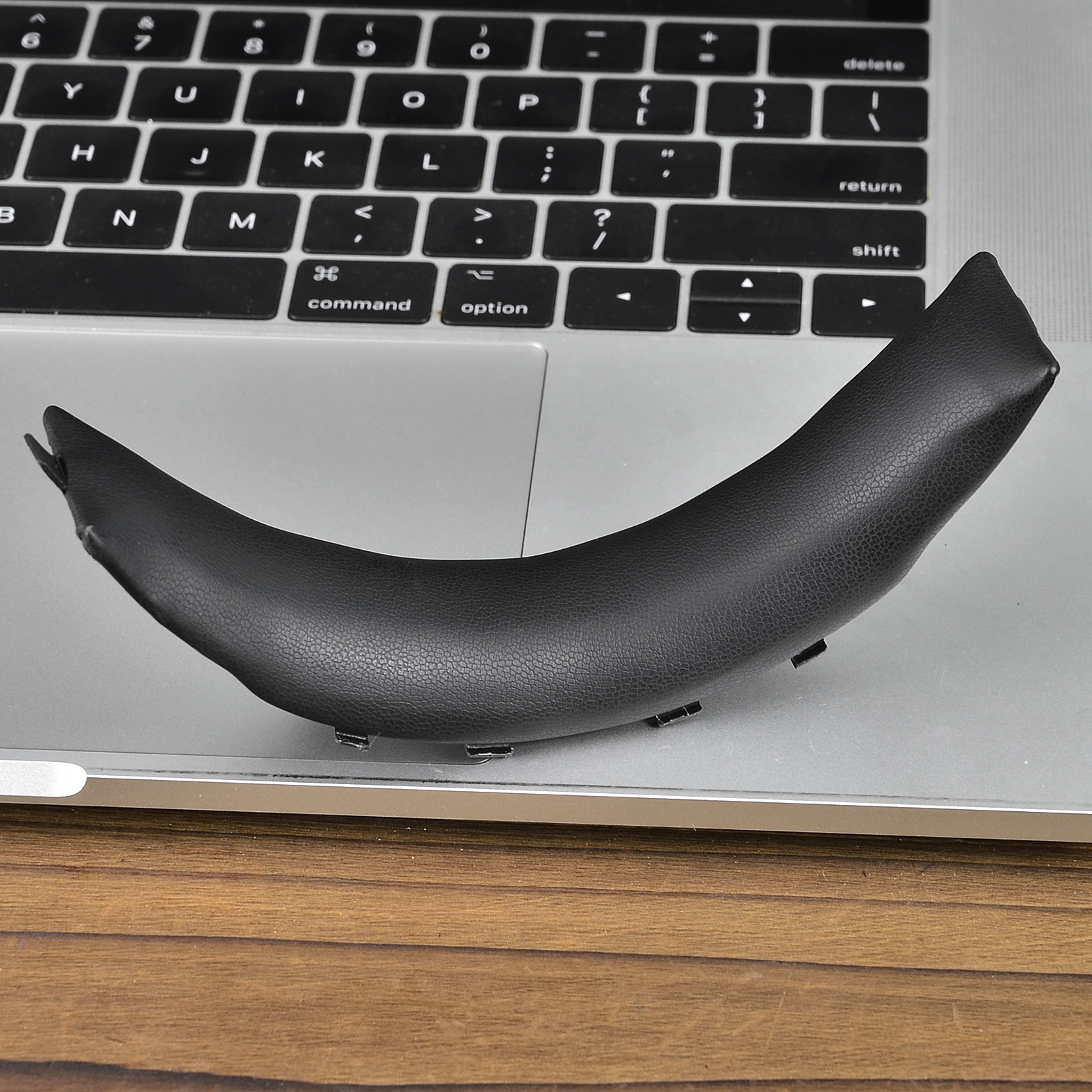 Czarna, zakrzywiona podpórka pod nadgarstek do laptopa na klawiaturze laptopa. Klawiatura jest czarna i srebrna.