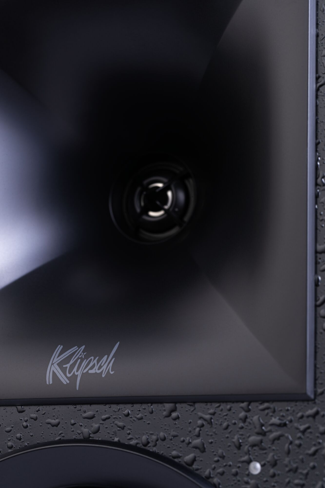 Primo piano dell'altoparlante nero. Logo Klipsch visibile. Gocce d'acqua.