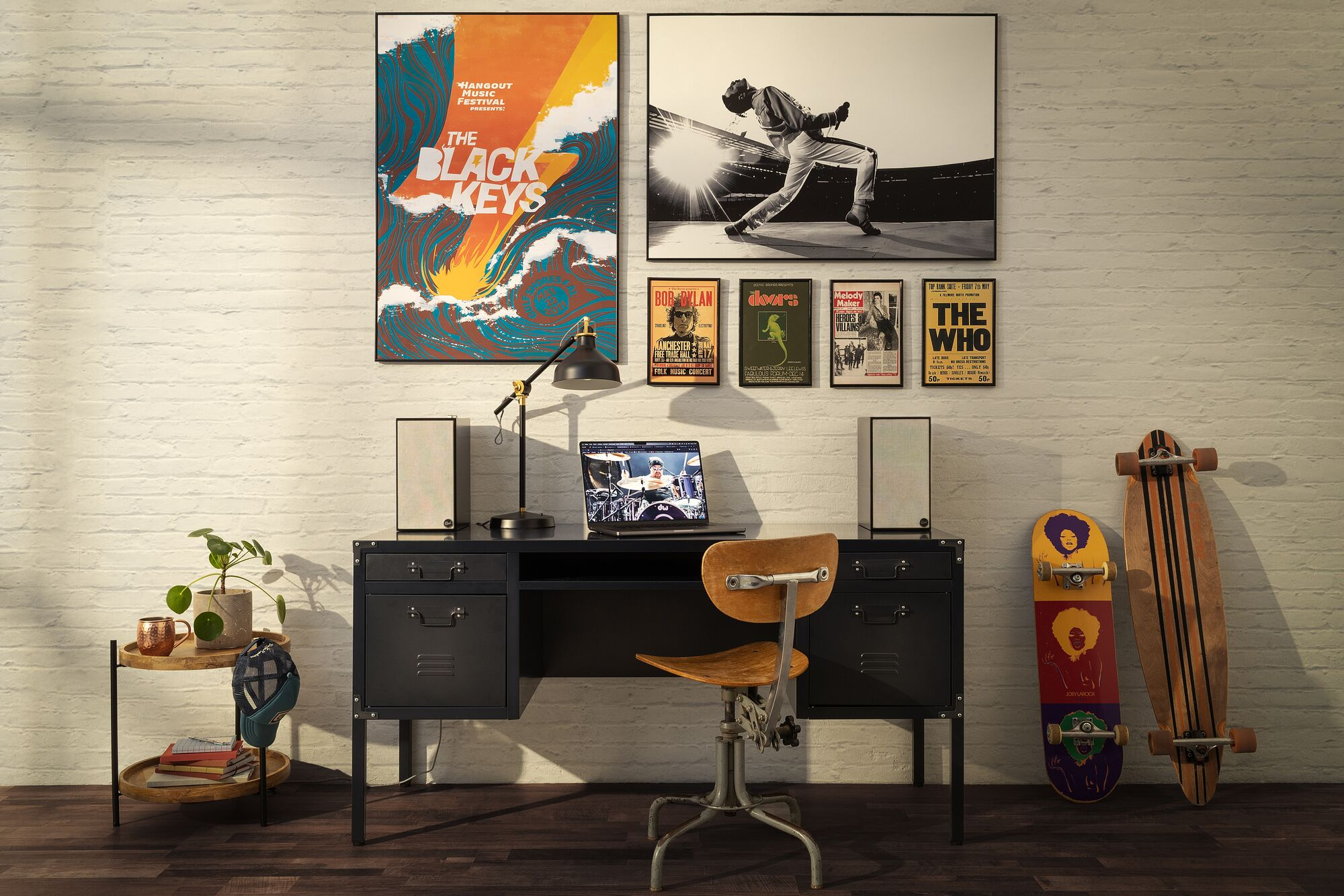 Una stanza con poster, una scrivania, altoparlanti e uno skateboard. Un laptop è aperto sulla scrivania.