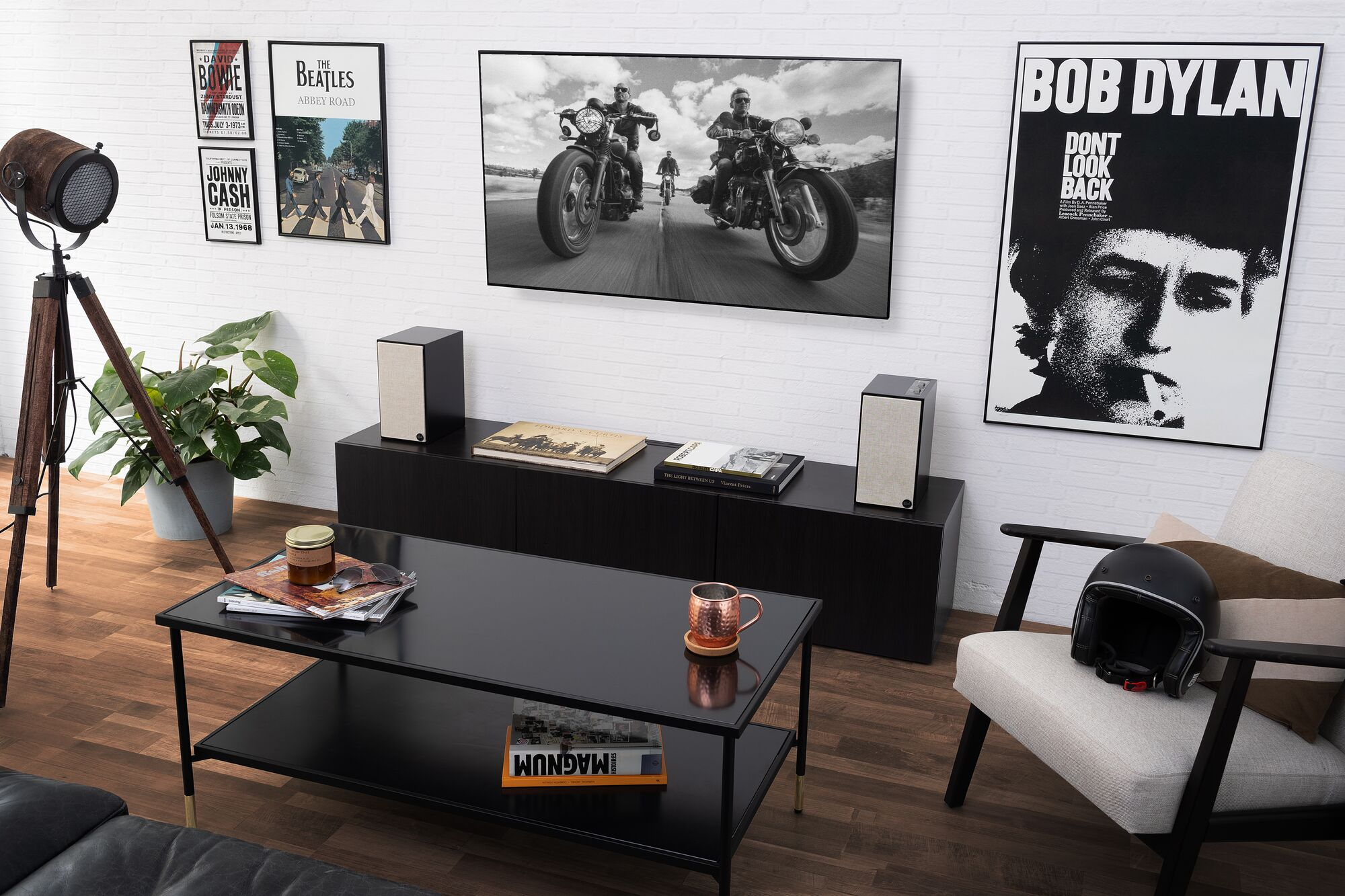 Configurazione del soggiorno: TV, altoparlanti, tavolino con decorazioni e poster. Pavimento in legno.