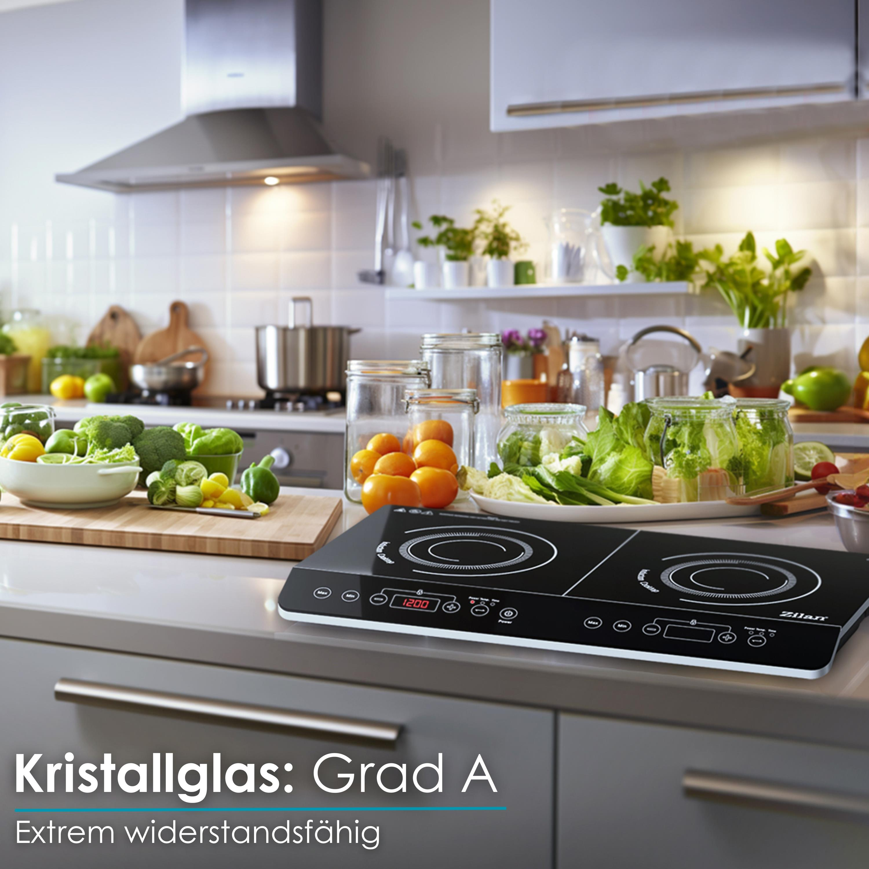 Küchentheke mit Induktionskochfeld und Gemüse. Hintergrund zeigt eine Küche mit weißen Fliesen.