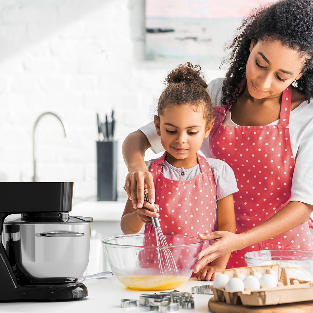 Een vrouw en een meisje koken samen. Ze gebruiken een mixer om ingrediënten in een kom te mengen.