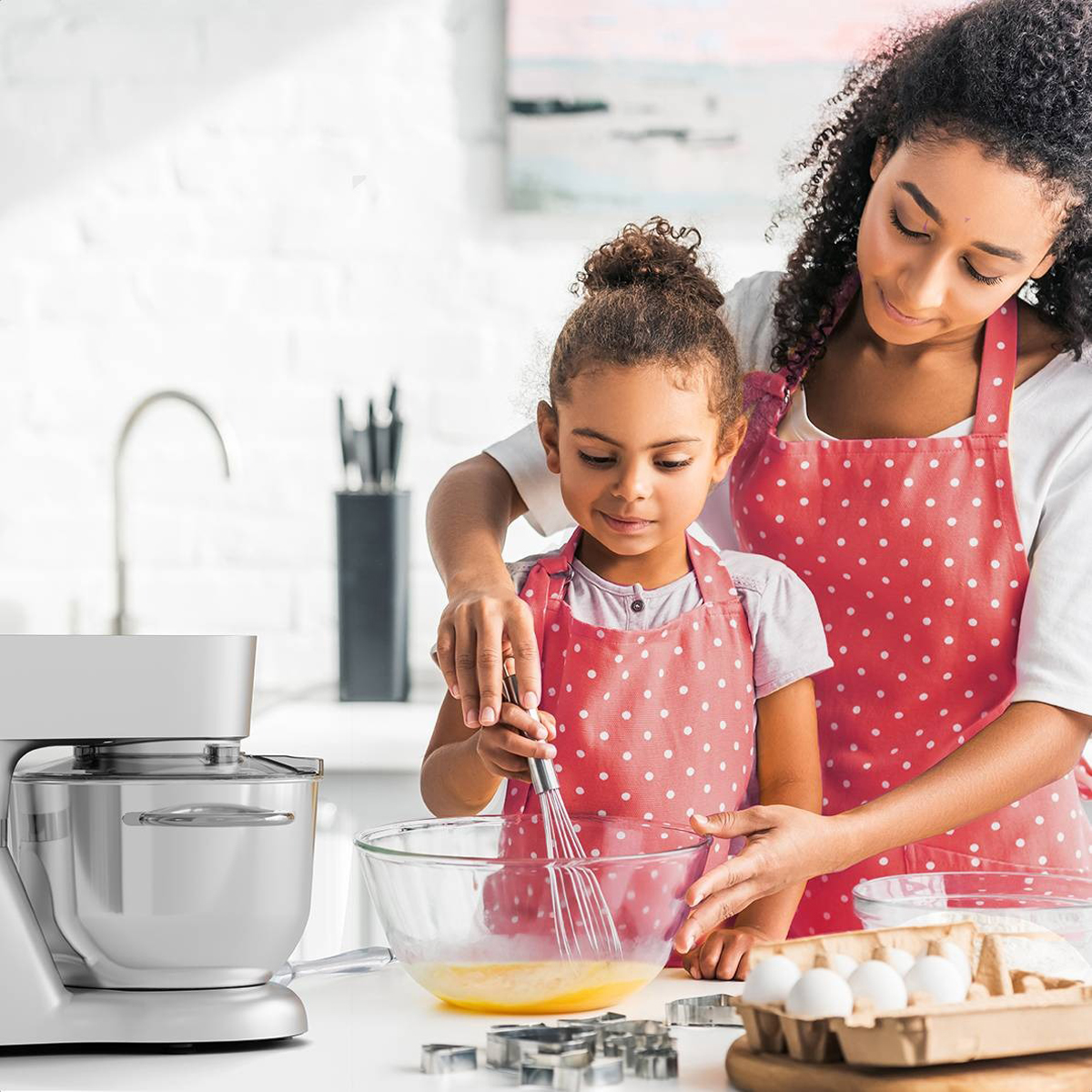 Een vrouw en een meisje zijn aan het koken. Ze kloppen ingrediënten in een glazen kom.