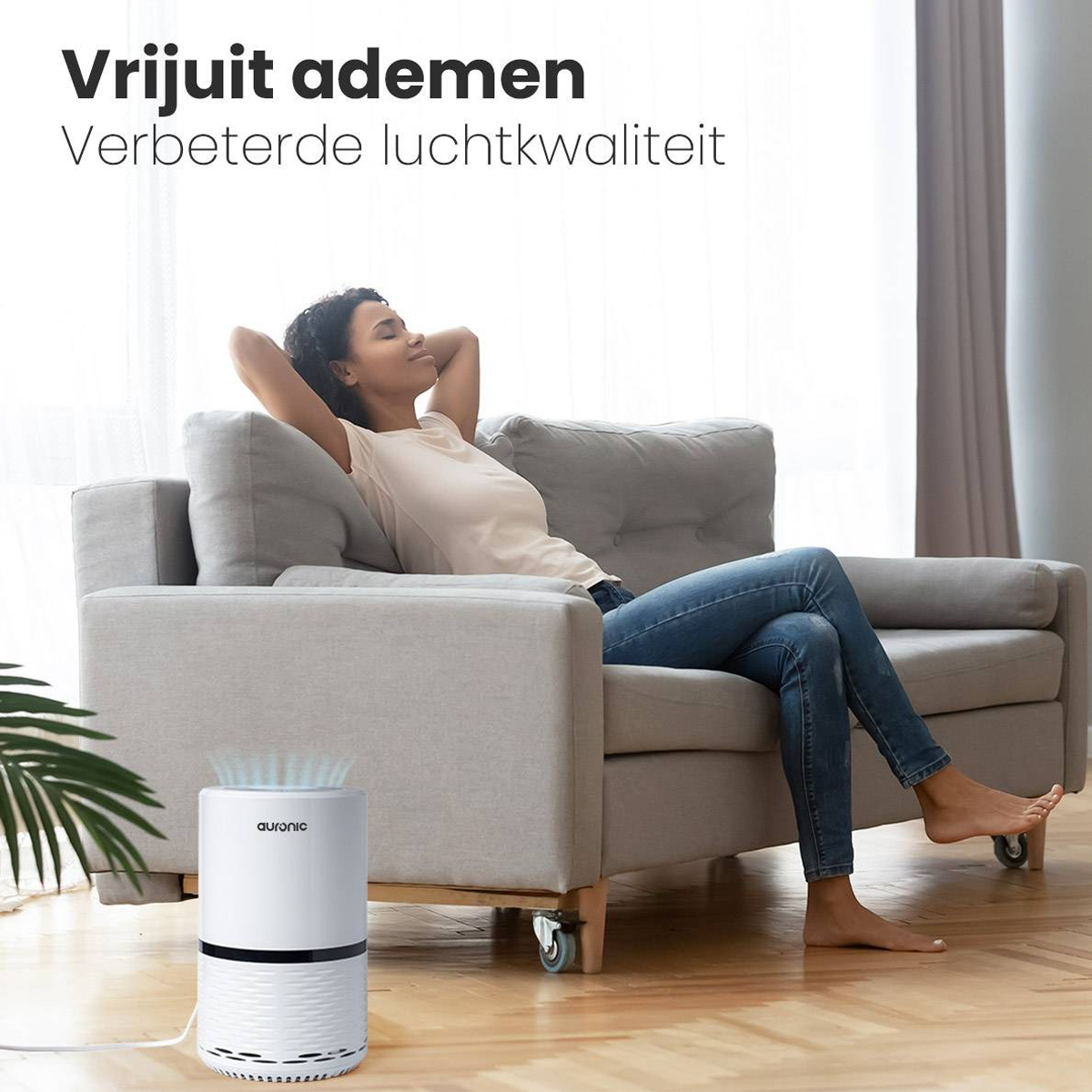 A woman relaxing on a couch. An air purifier sits on the floor in the foreground.