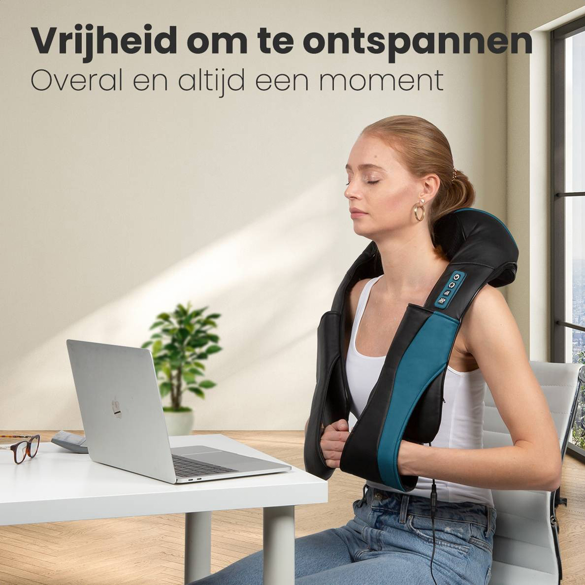 Woman wearing a black and teal neck massager, sitting by a laptop on a white table.