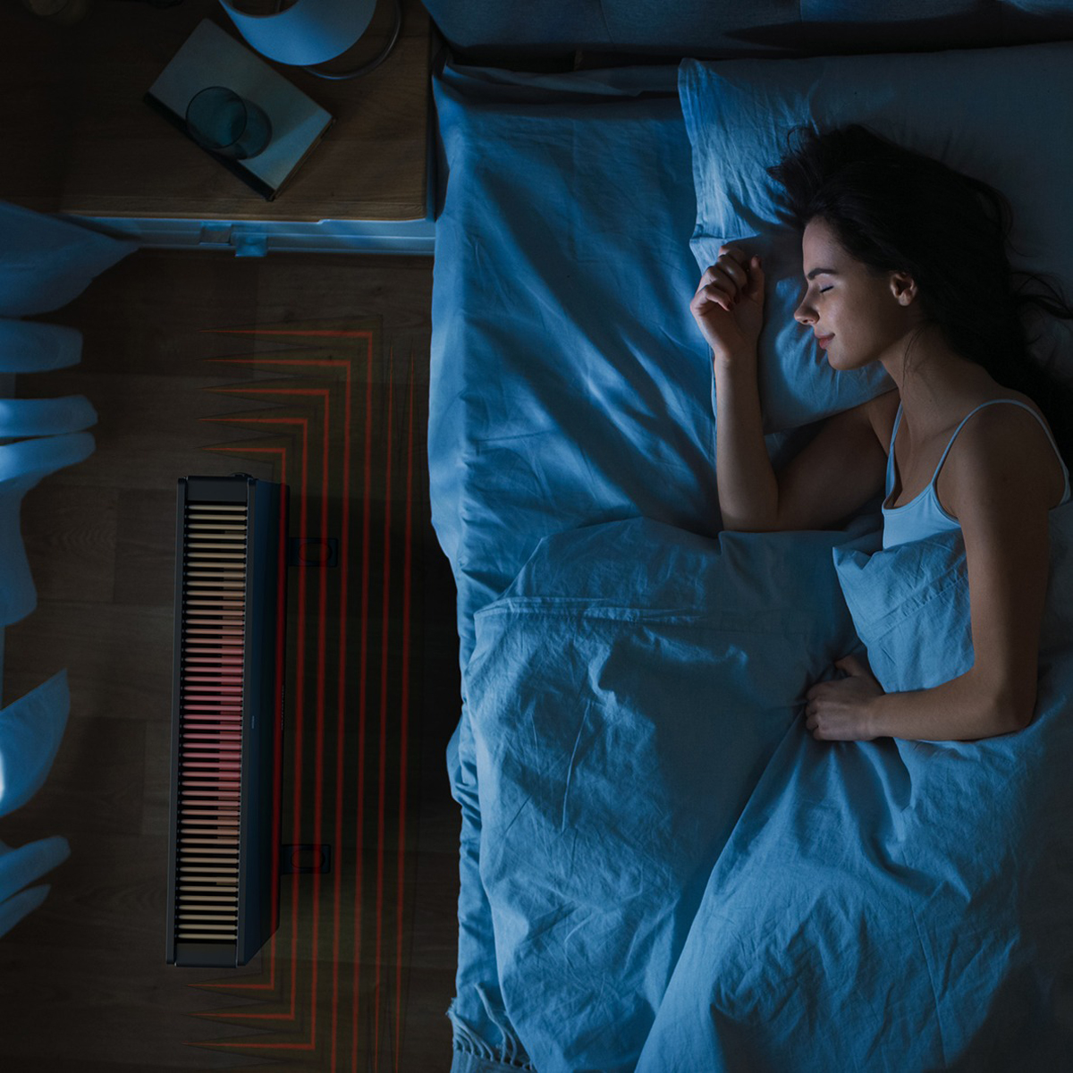 A woman sleeping in bed next to a floor heater with red lights.