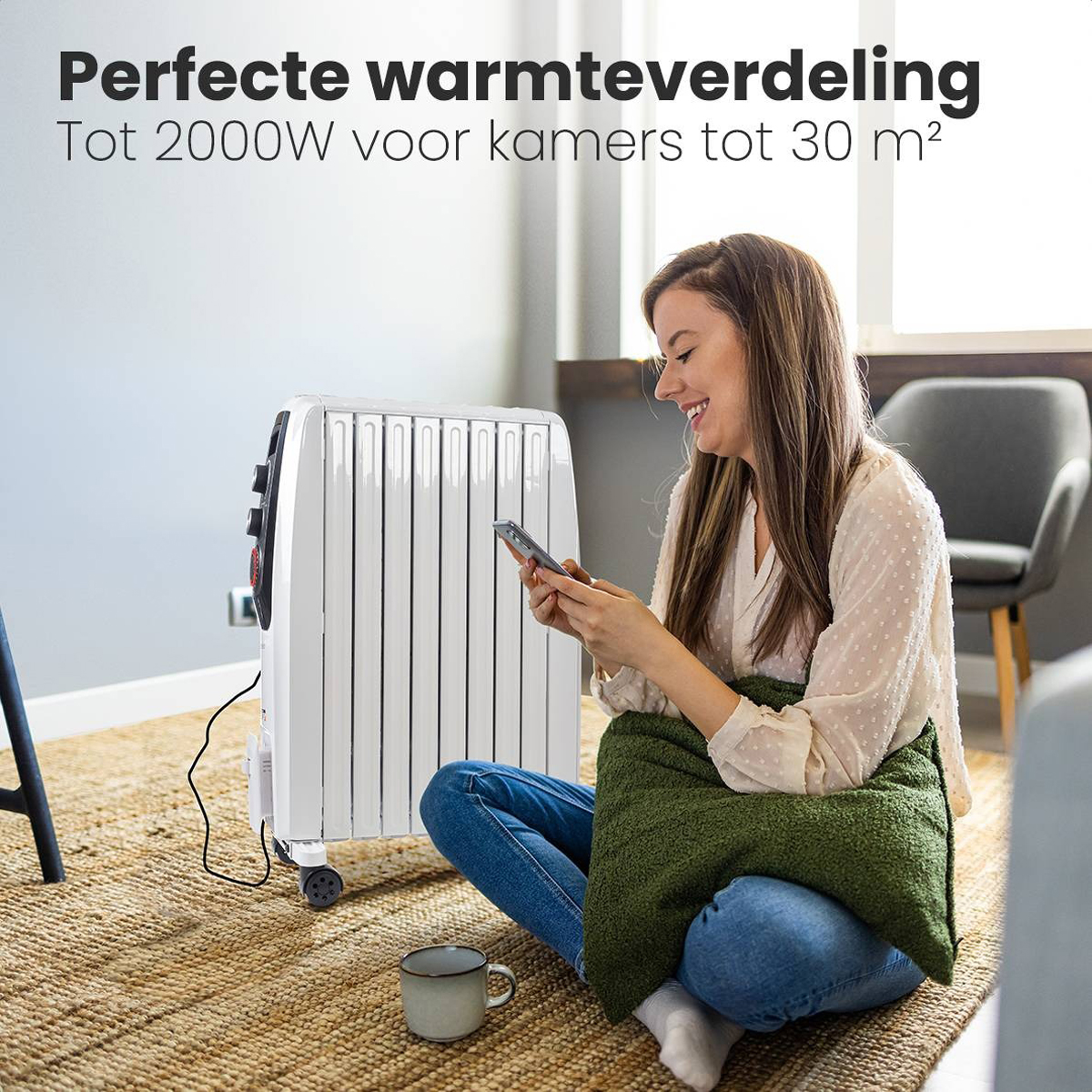 Vrouw gebruikt telefoon bij witte radiator. Mok en groen kussen op de voorgrond.