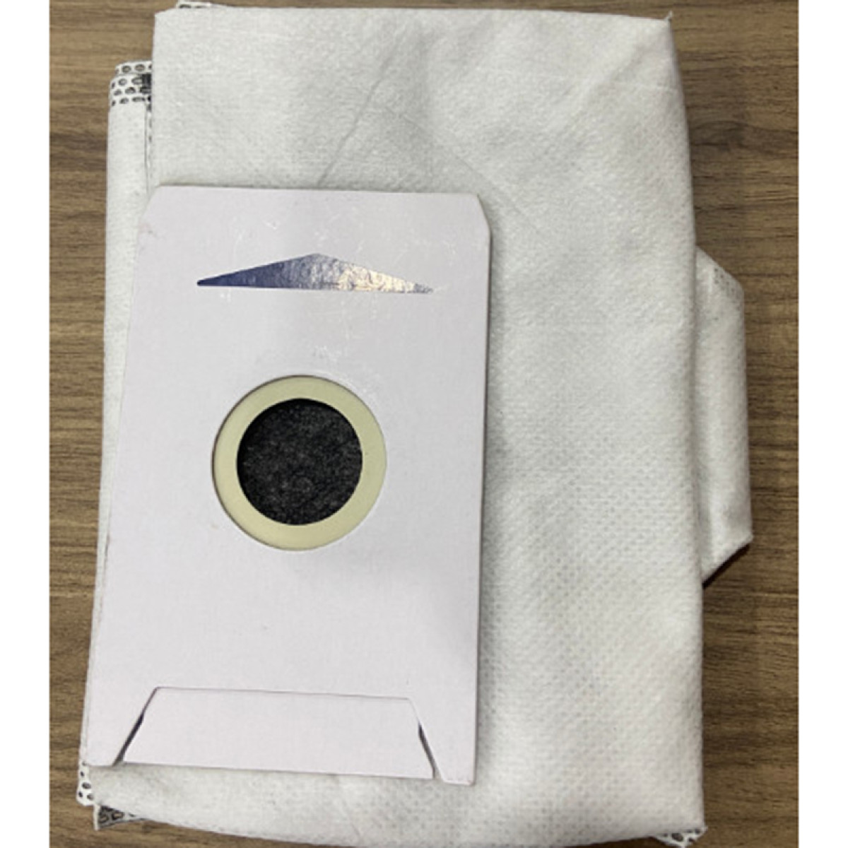 Weißer Staubsaugerbeutel mit rundem Filter und weißem Papierbeutel.
