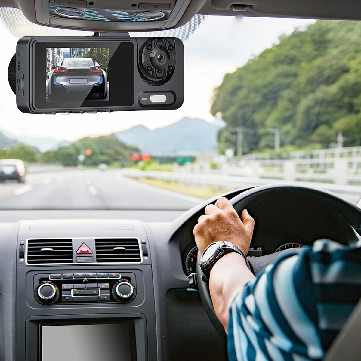 Armaturenbrett eines Autos und eine Hand am Lenkrad mit einer Dashcam auf der Windschutzscheibe.
