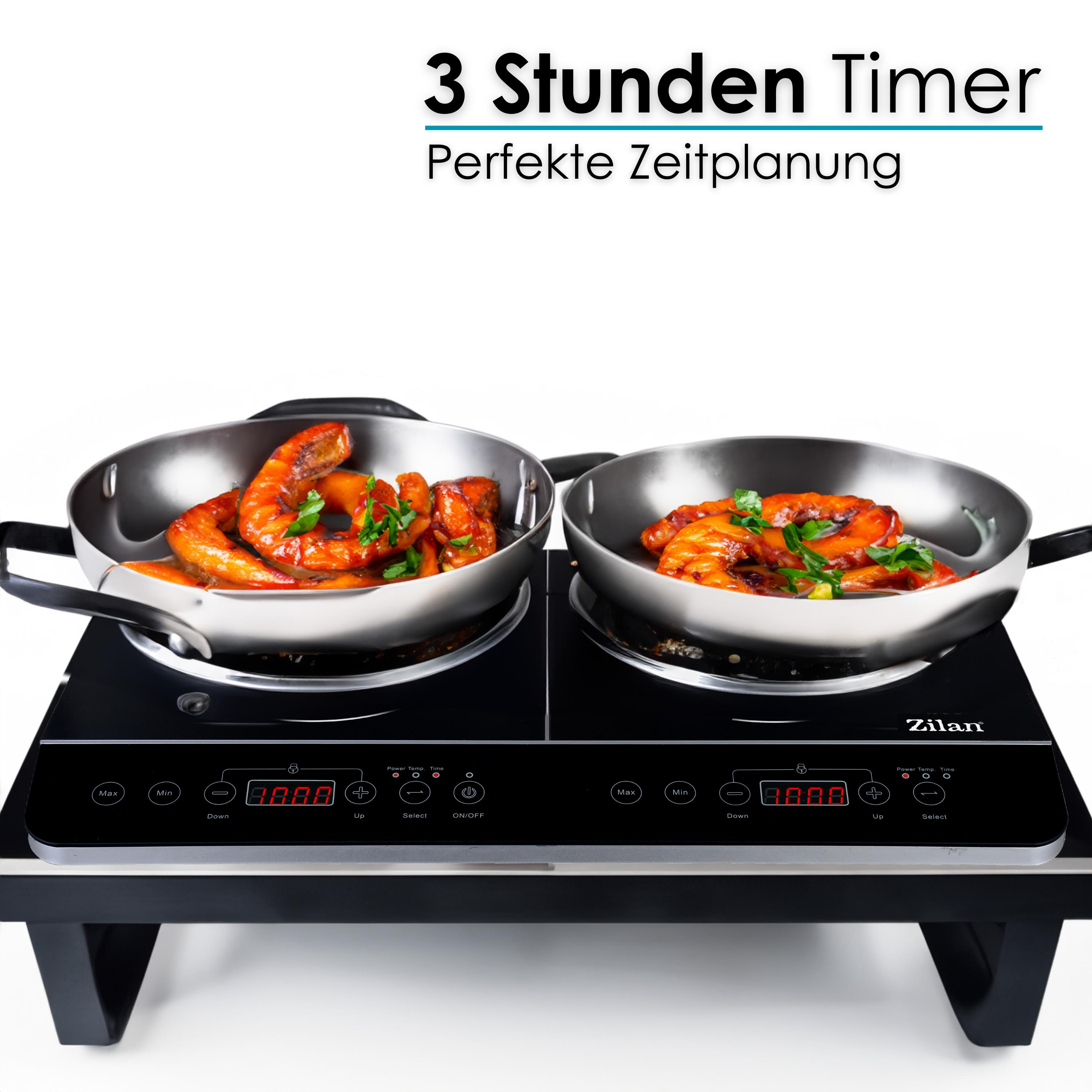 Induktionskochfeld mit Doppelbrennern und Essen in Pfannen. Das Kochfeld ist schwarz.