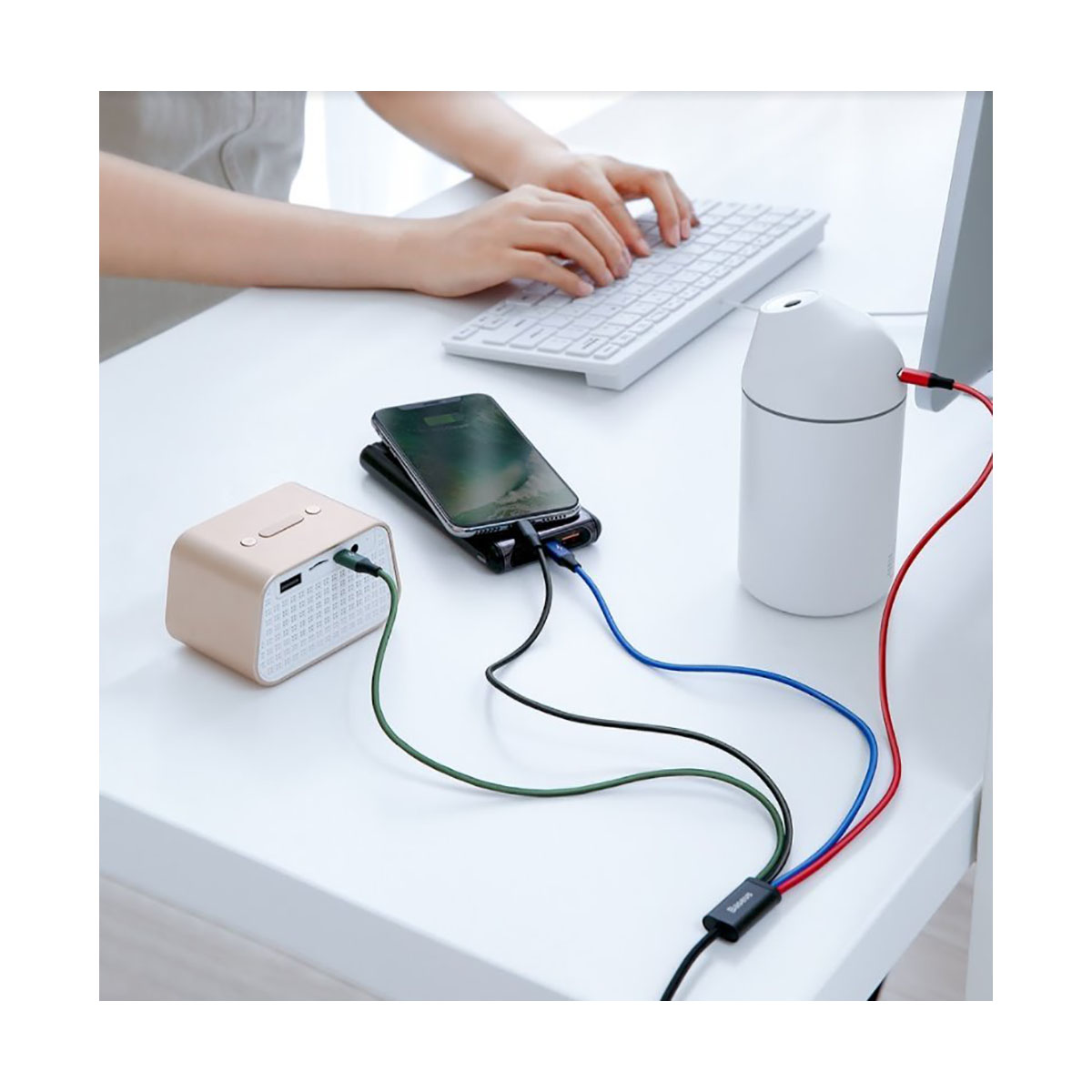 Biurko z klawiaturą, ładowaniem telefonu i nawilżaczem z kolorowymi kablami.