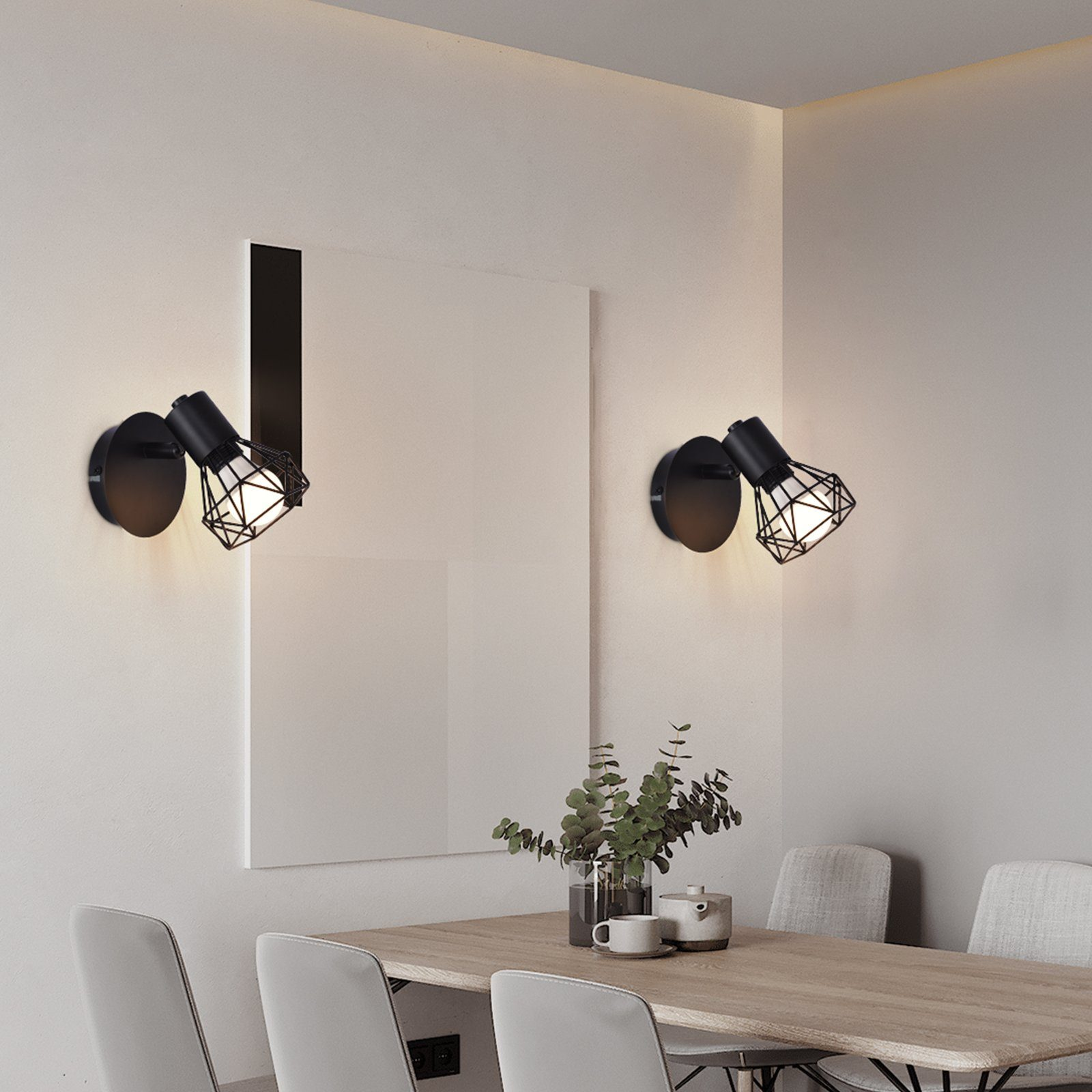 Dos lámparas de pared negras con diseño de jaula, montadas en una pared blanca.