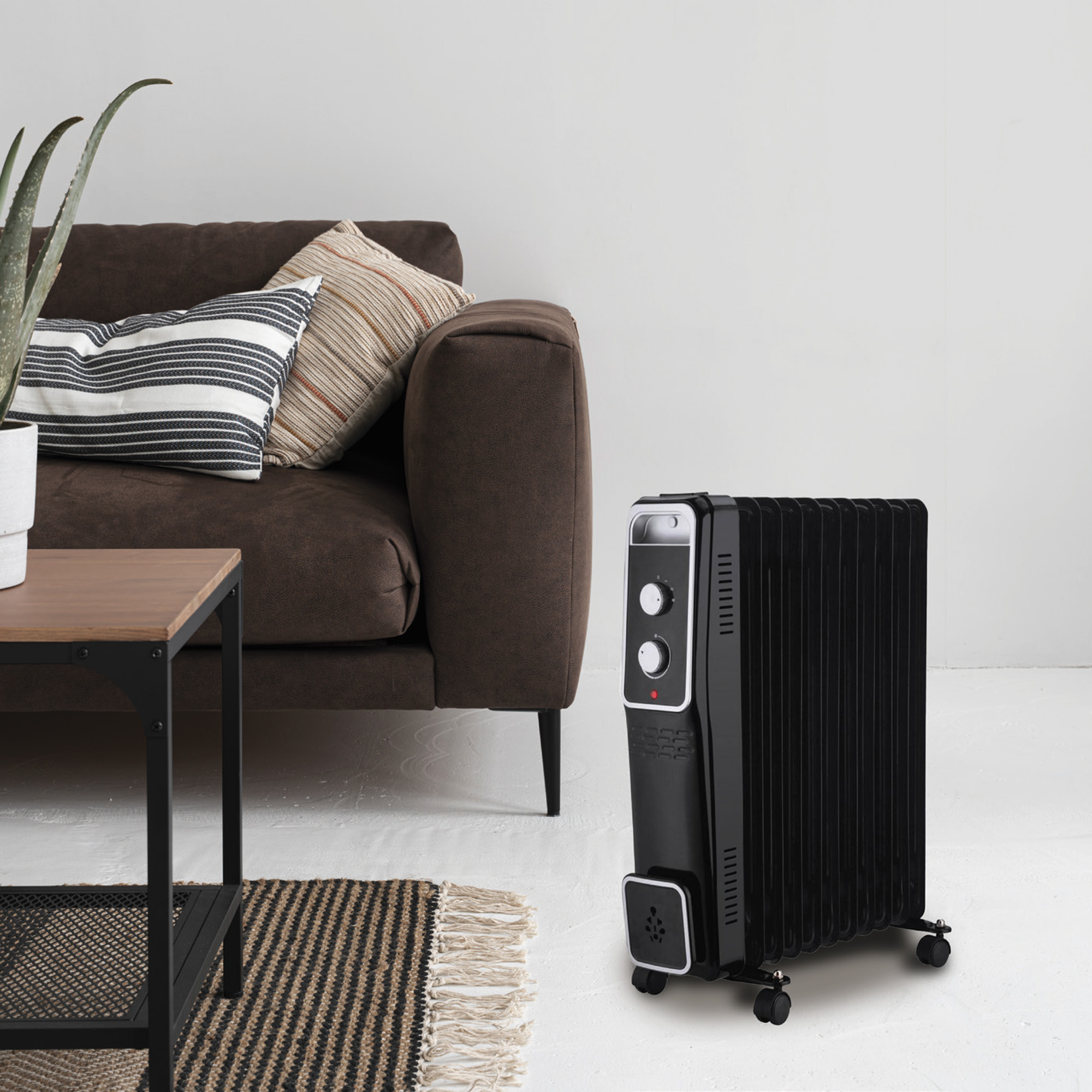 Schwarzer, ölbeheizter Heizkörper in einem Wohnzimmer, in der Nähe eines braunen Sofas und eines Teppichs.
