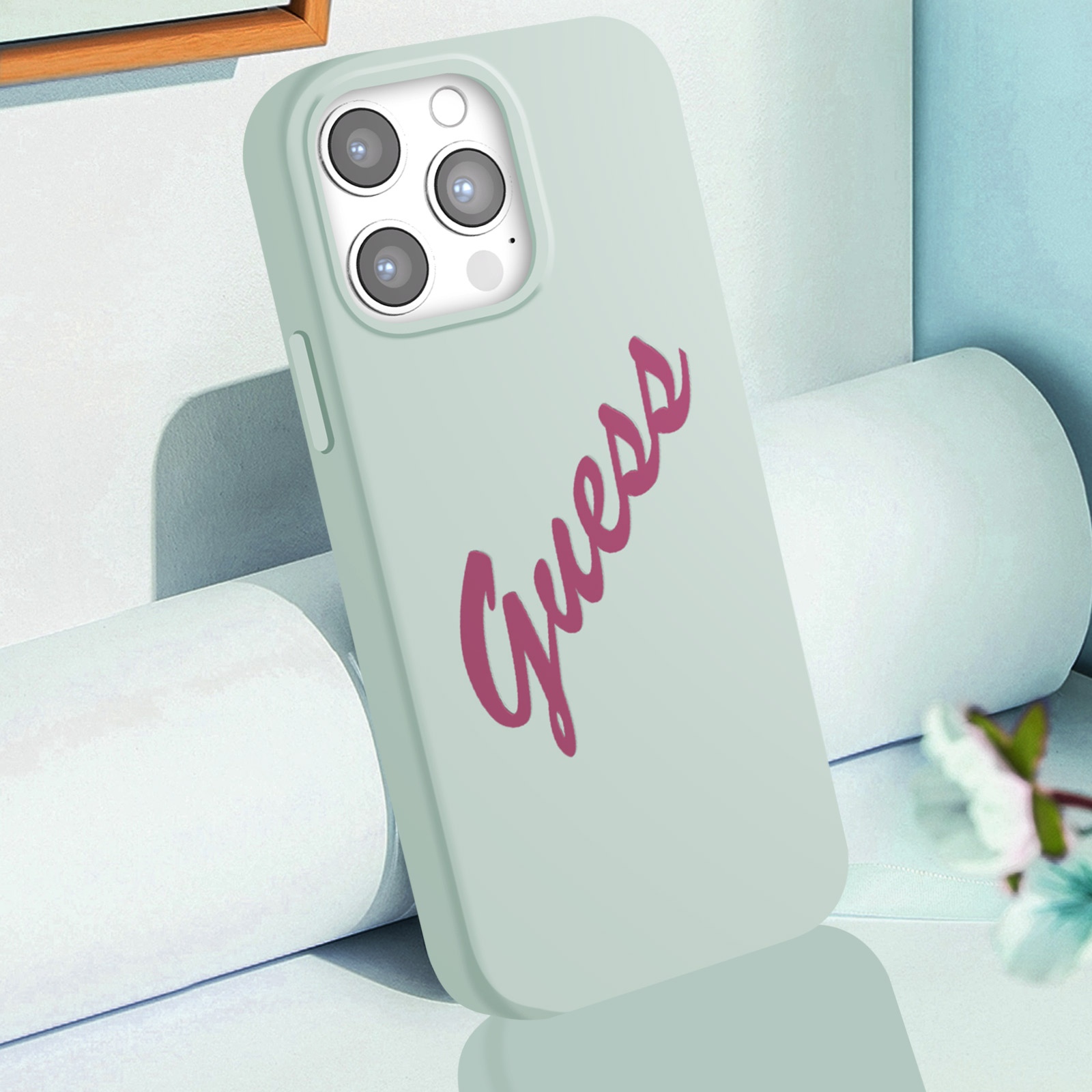 Una custodia per telefono verde chiaro con la scritta 'Guess' in corsivo rosa.