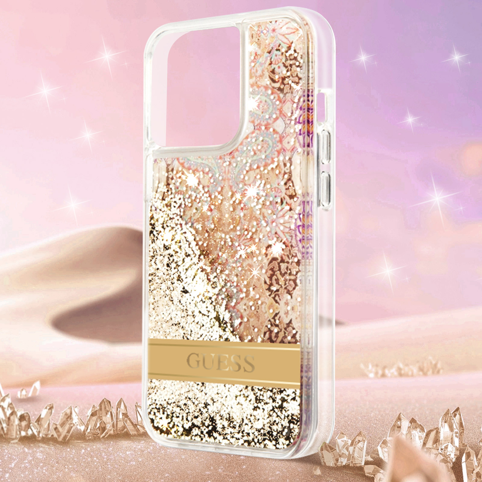 Custodia trasparente per telefono con glitter dorati e il logo Guess. Contro una scena desertica.