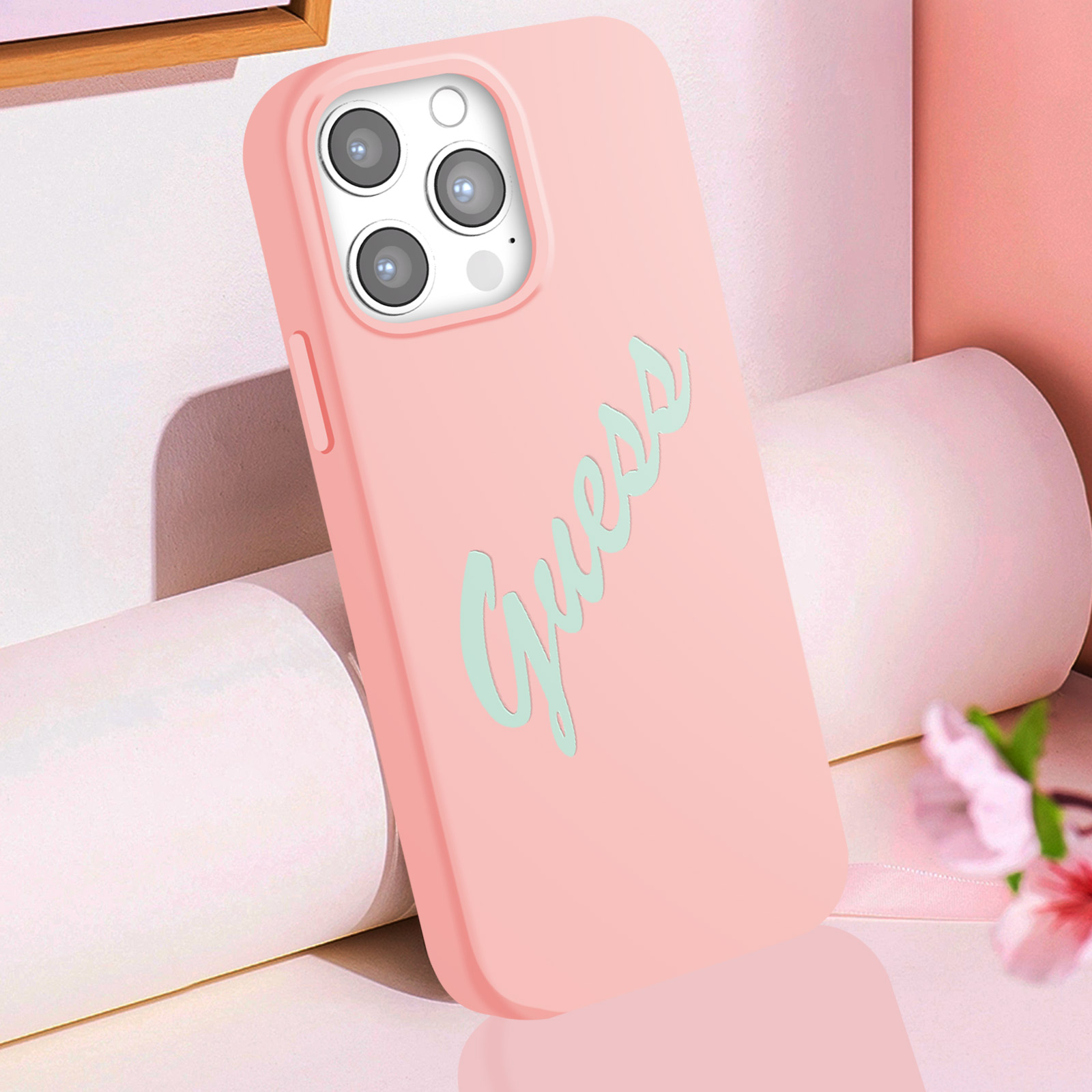 Una custodia per telefono rosa con "Guess" scritto in azzurro su sfondo rosa.