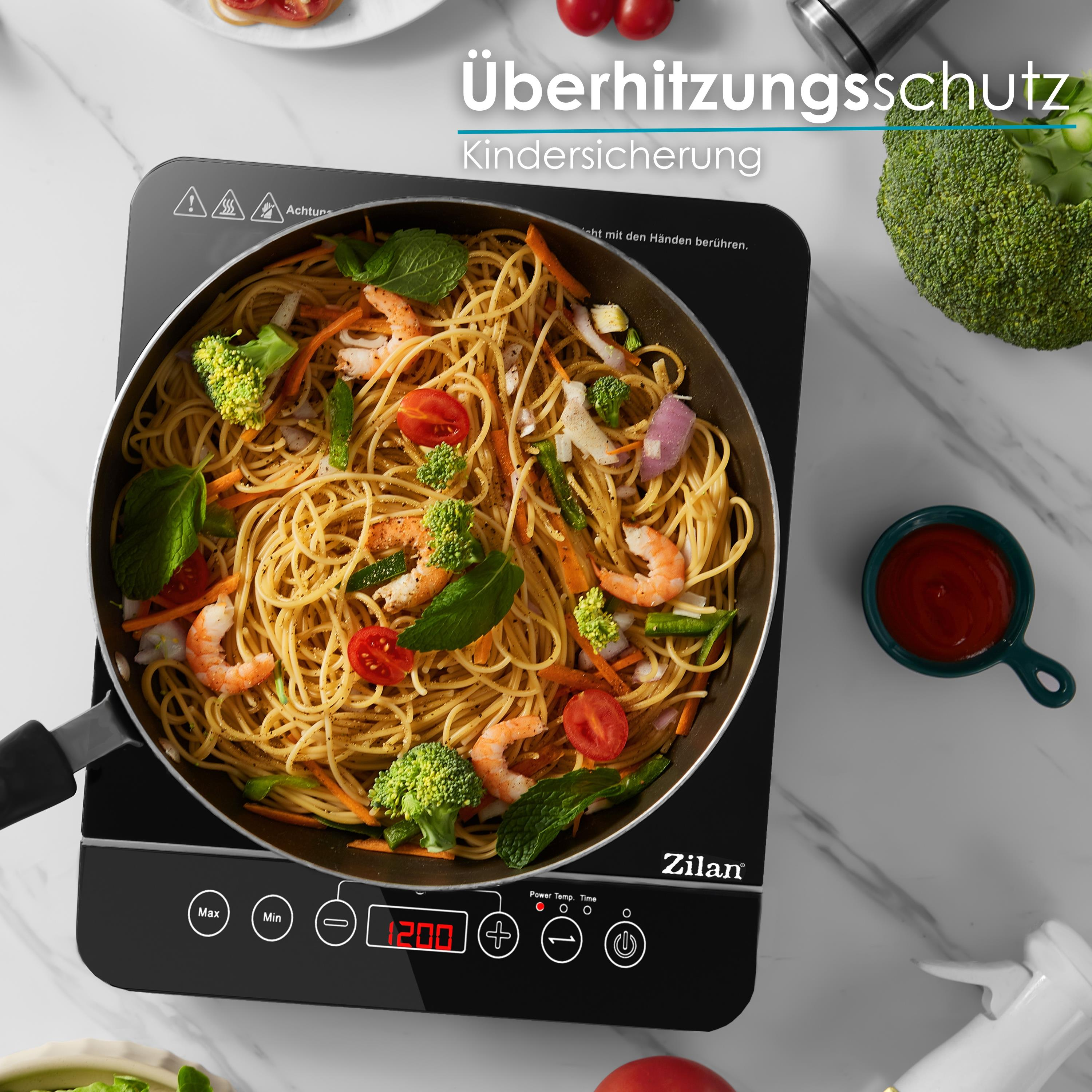 Spaghetti mit Garnelen und Gemüse, die auf einem schwarzen Induktionskochfeld gekocht werden.